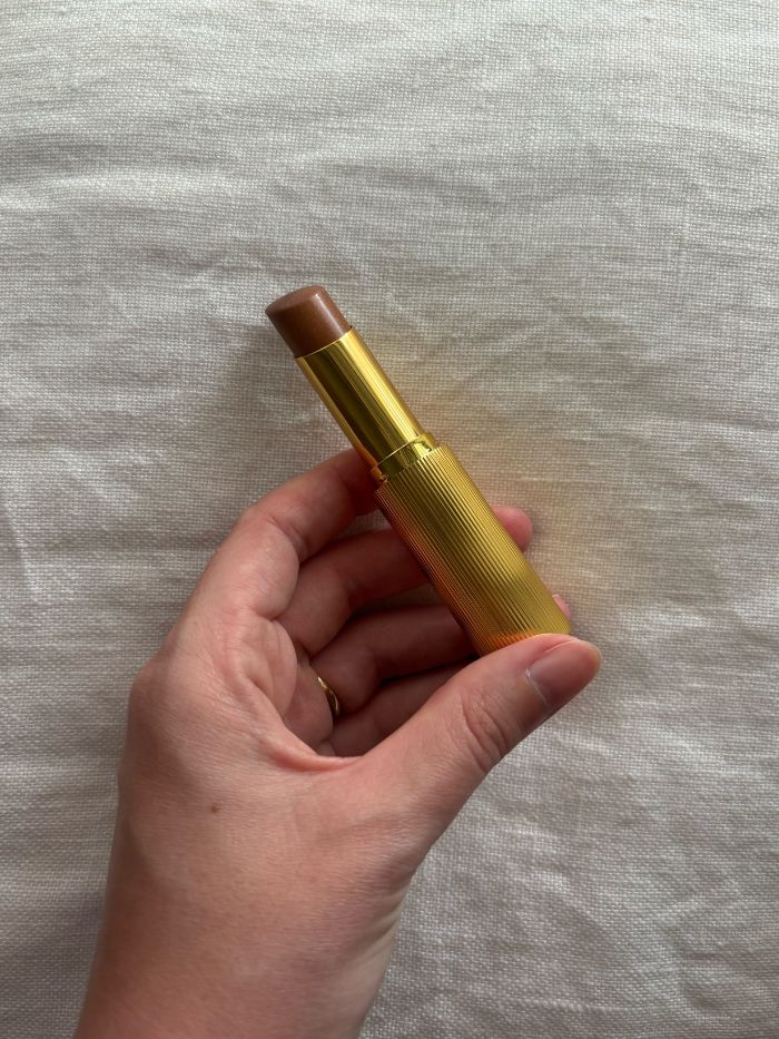 Deputy beauty editor Grace Lindsay holding the Victoria Beckham Beauty Reflect Highlighter Stick