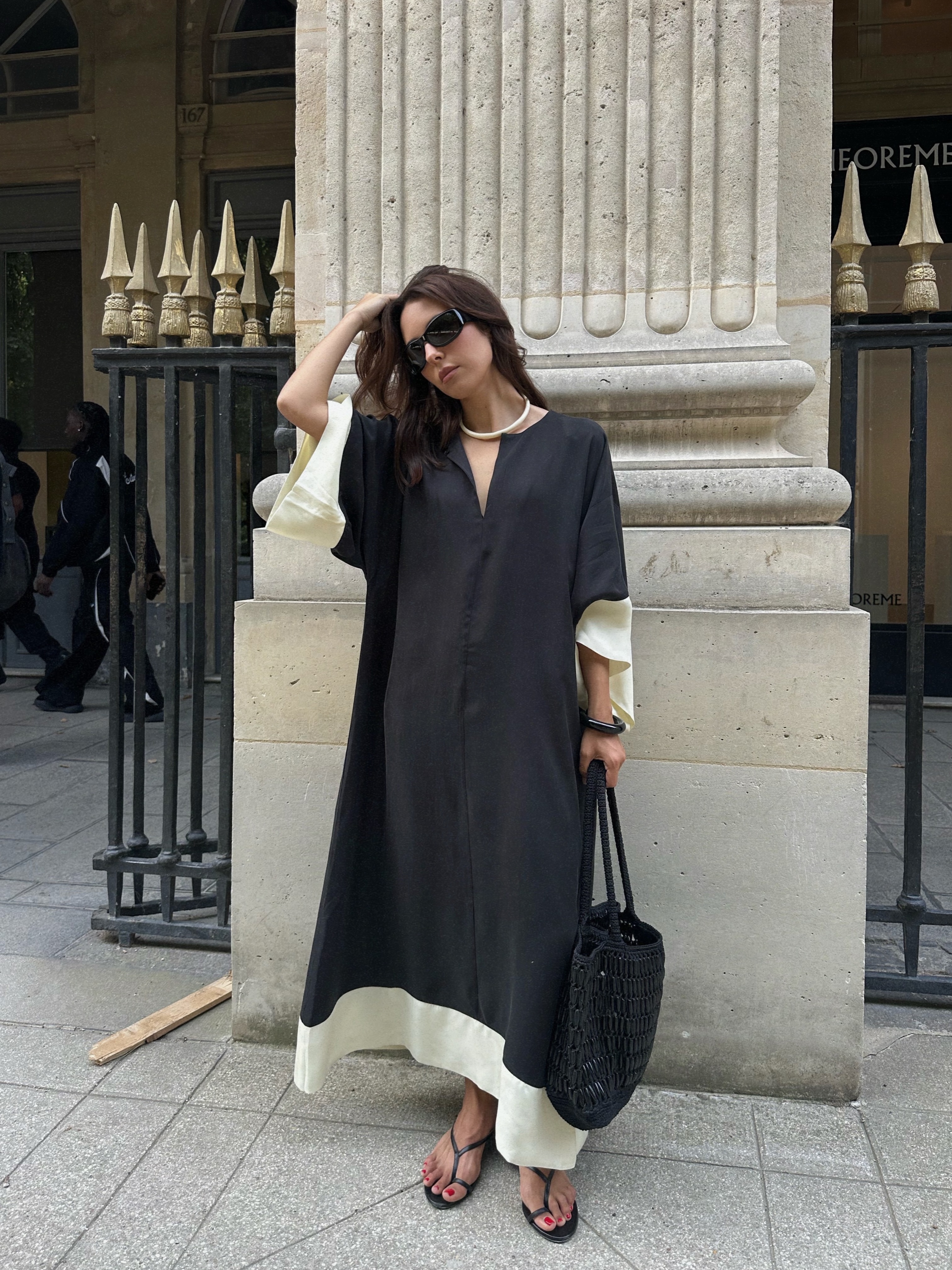 debora brosa wears a black kaftan, flip flops and a basket bag