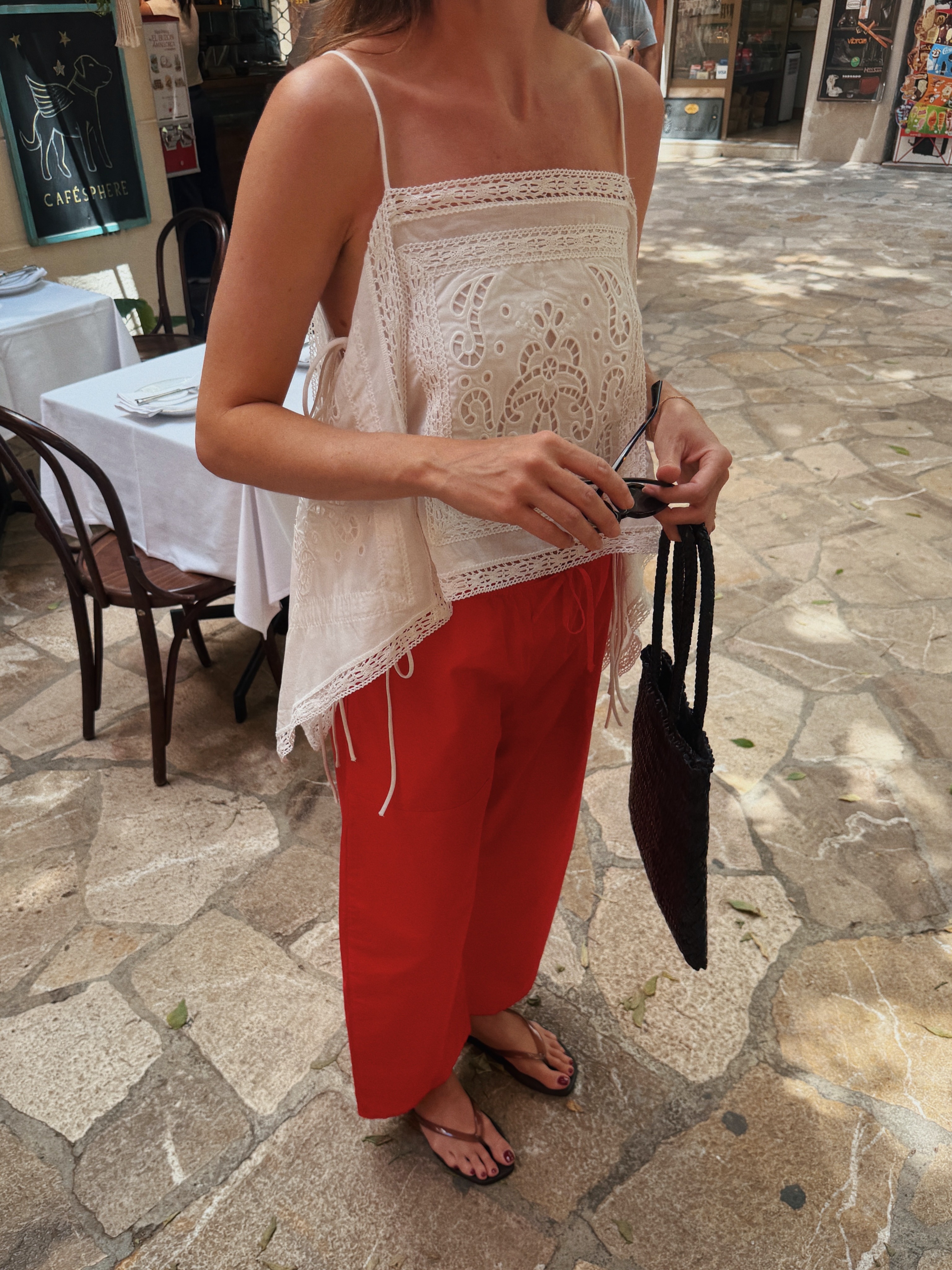 Woman in red poplin pants and a white embroidered top.