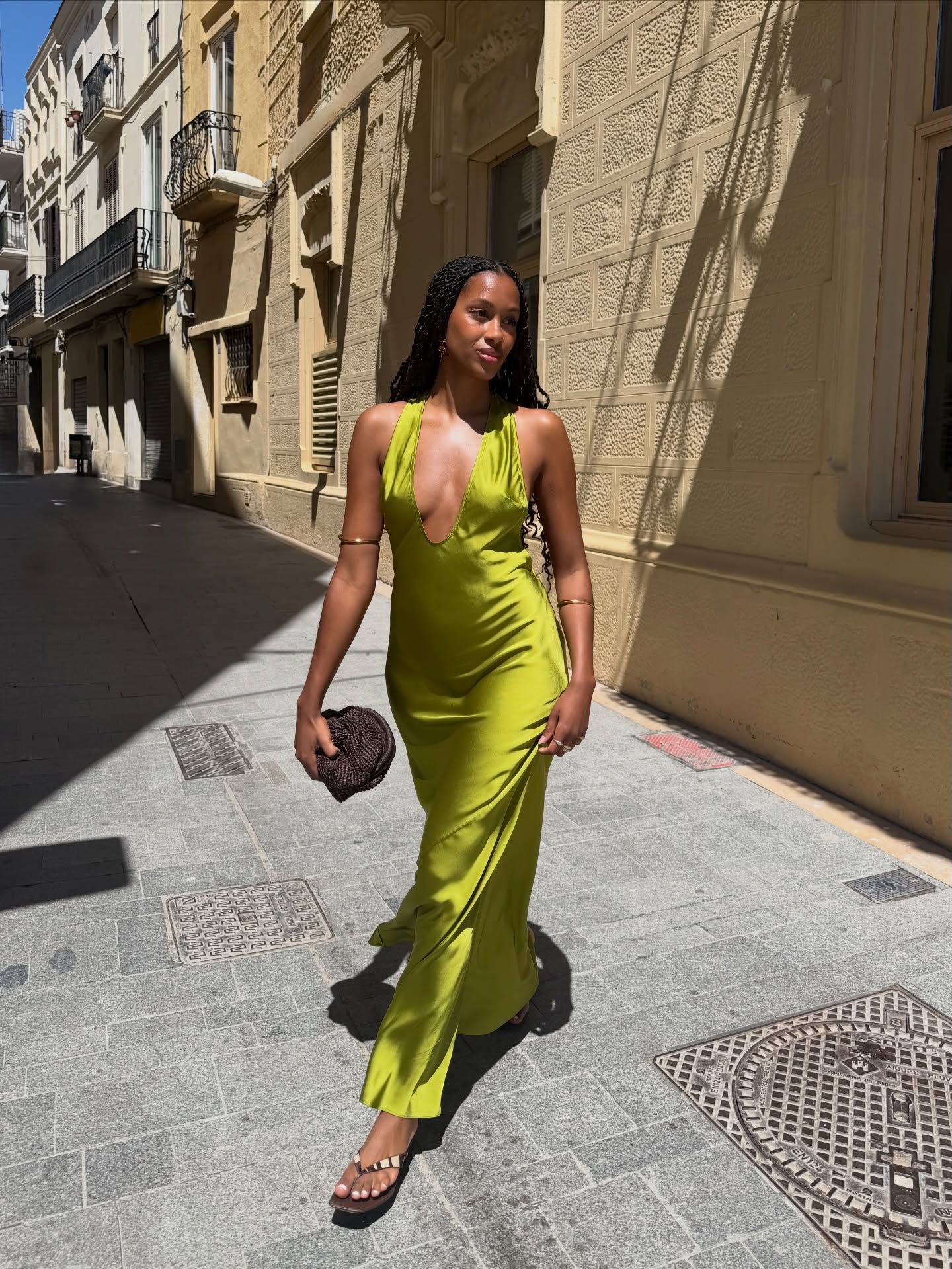 Claire in a green dress holding a woven frame clutch