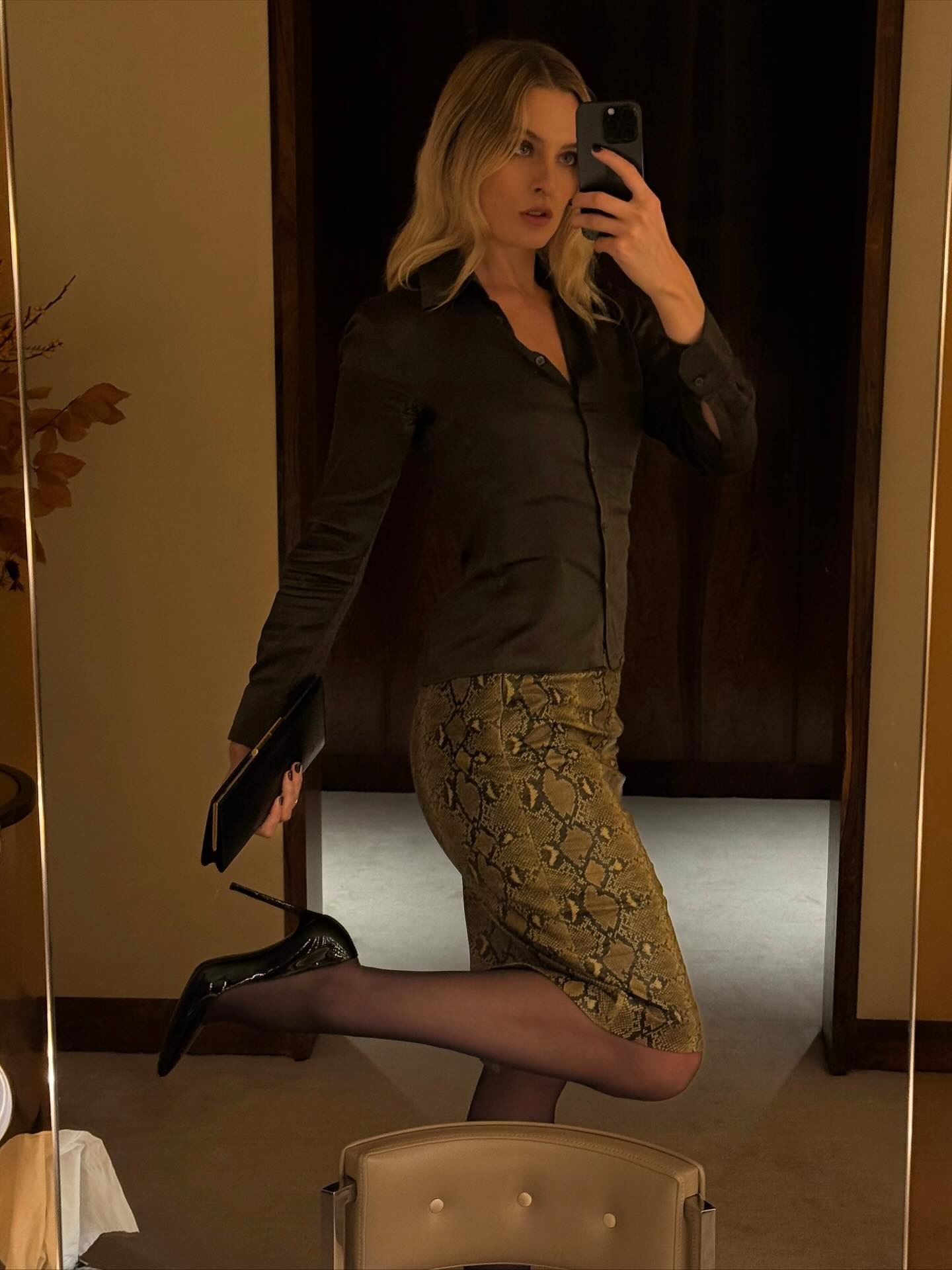 Christie Tyler wearing a button-down shirt, a snakeskin skirt, and pumps.