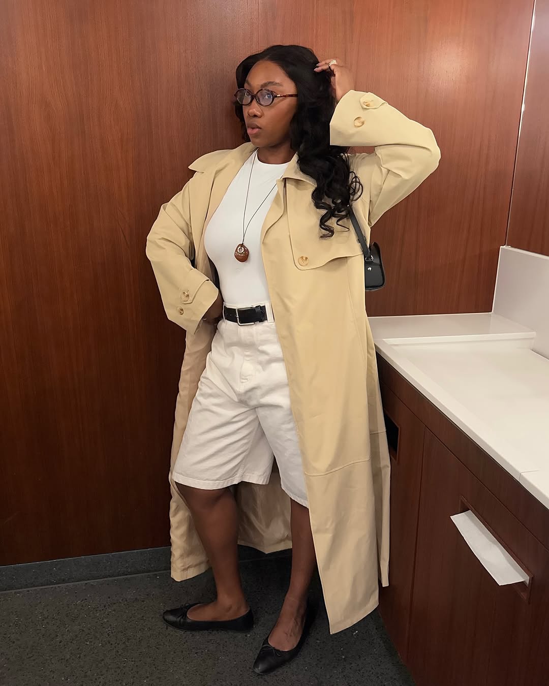 woman wearing long white shorts and long trench coat with ballet flats
