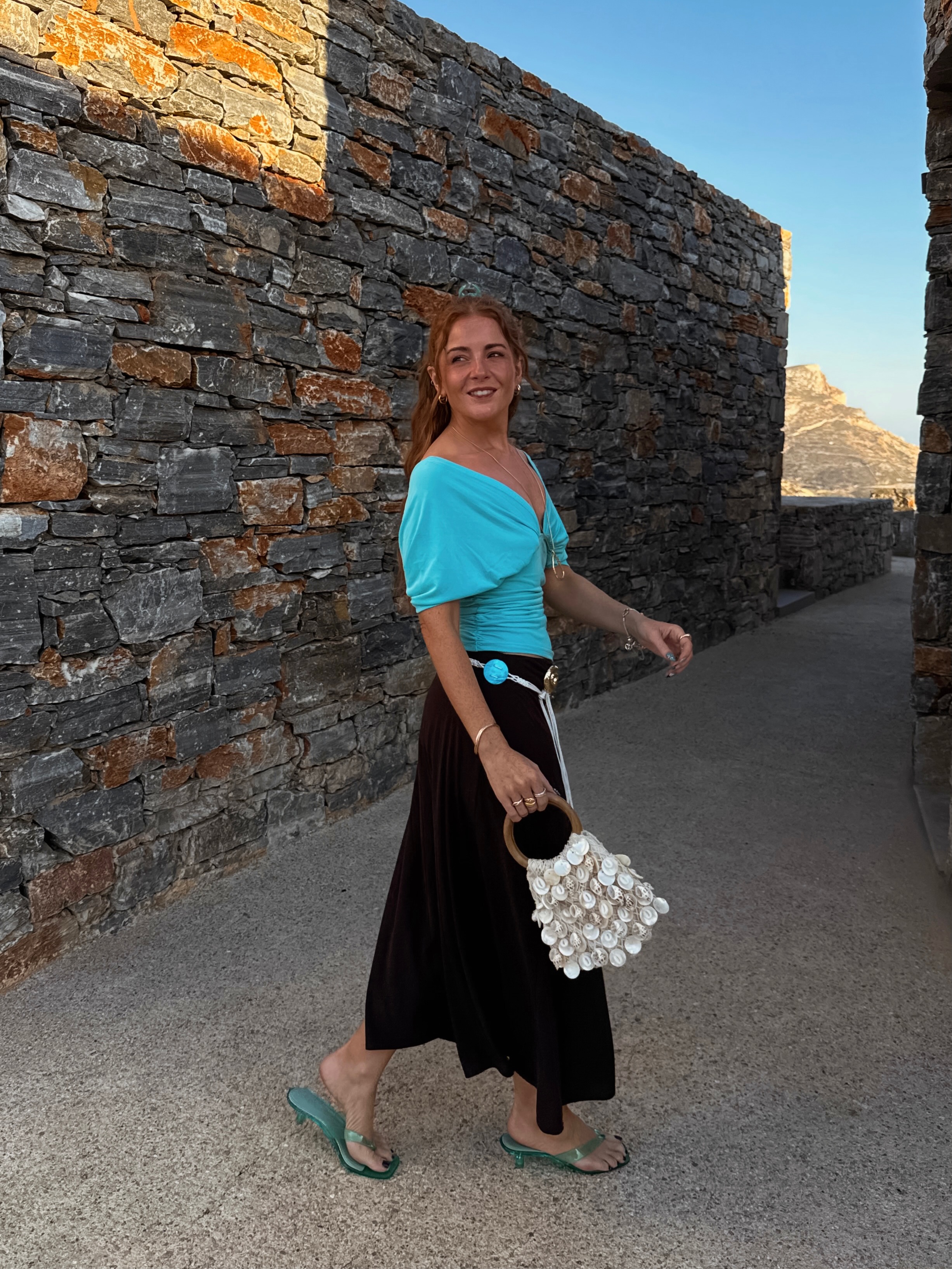Influencer Rebecca Ferraz Wyatt wearing a turquoise top, brown handkerchief skirt, jelly sandals, shell bag and rope belt.