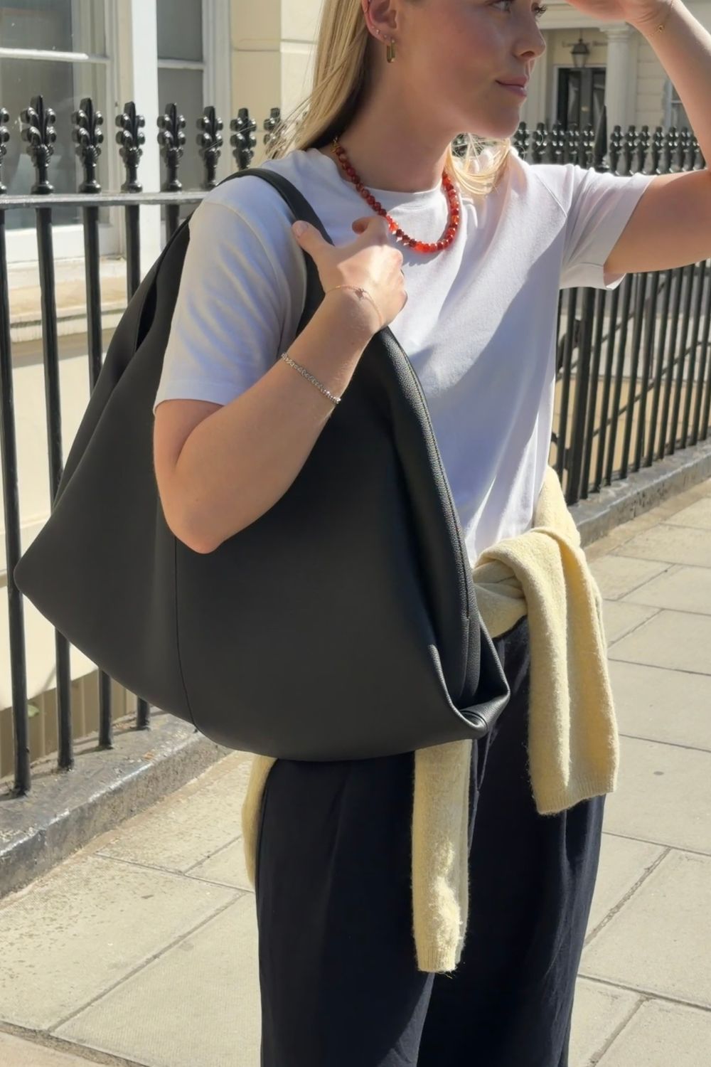 Woman wears White t-shirt, black linen trousers, yellow cardigan and black shoulder bag