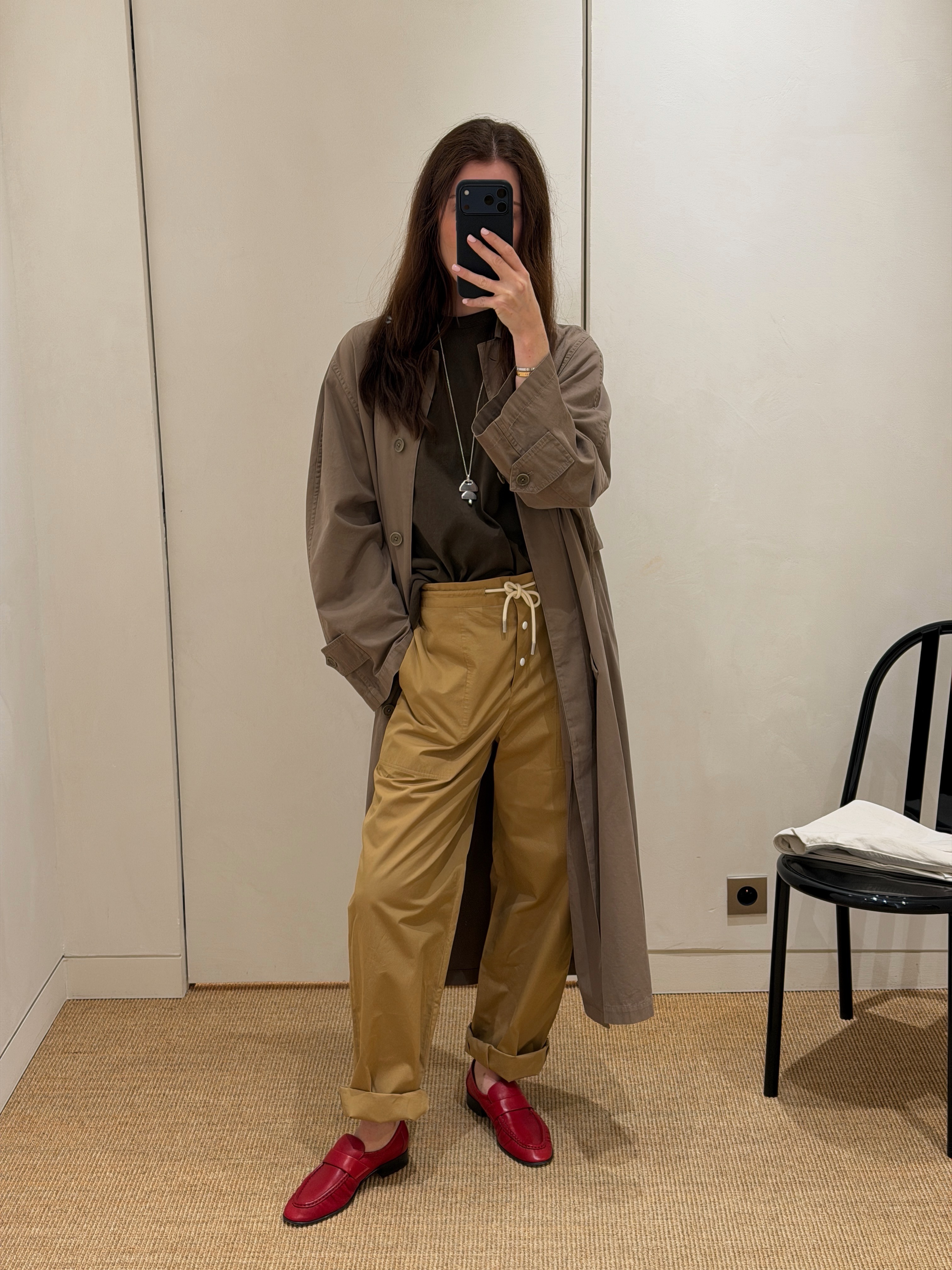 Influencer wearing dark beige pants with an olive trench and red loafers