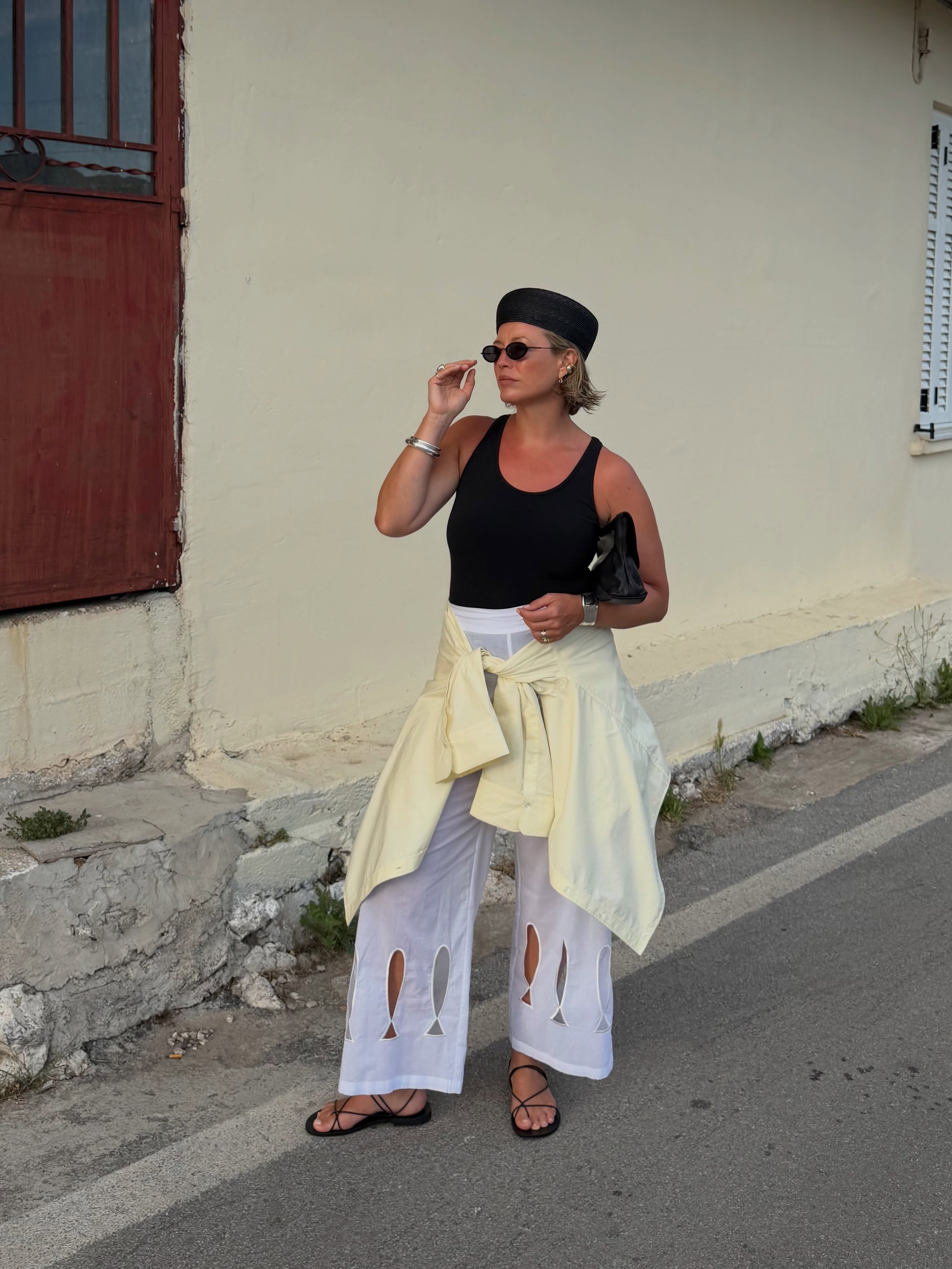 Alexis in white trousers, yellow blouse and black vest