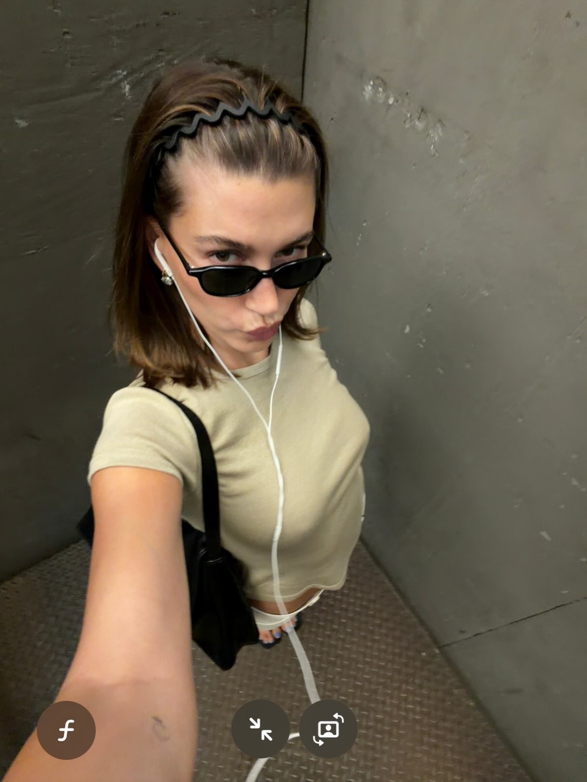 Hailey Bieber taking a selfie wearing a headband