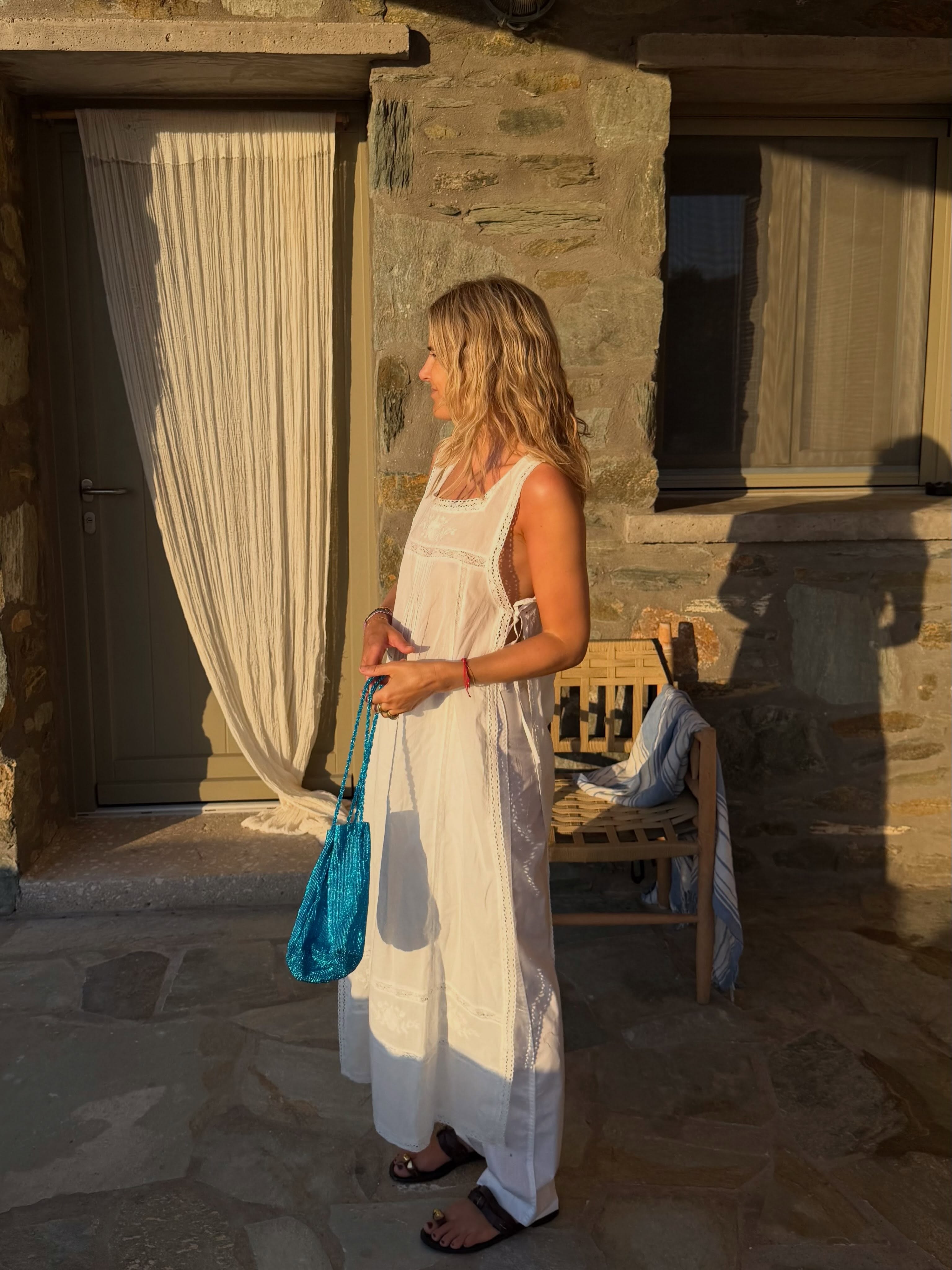 Lucy in long white top and trousers with aqua handbag