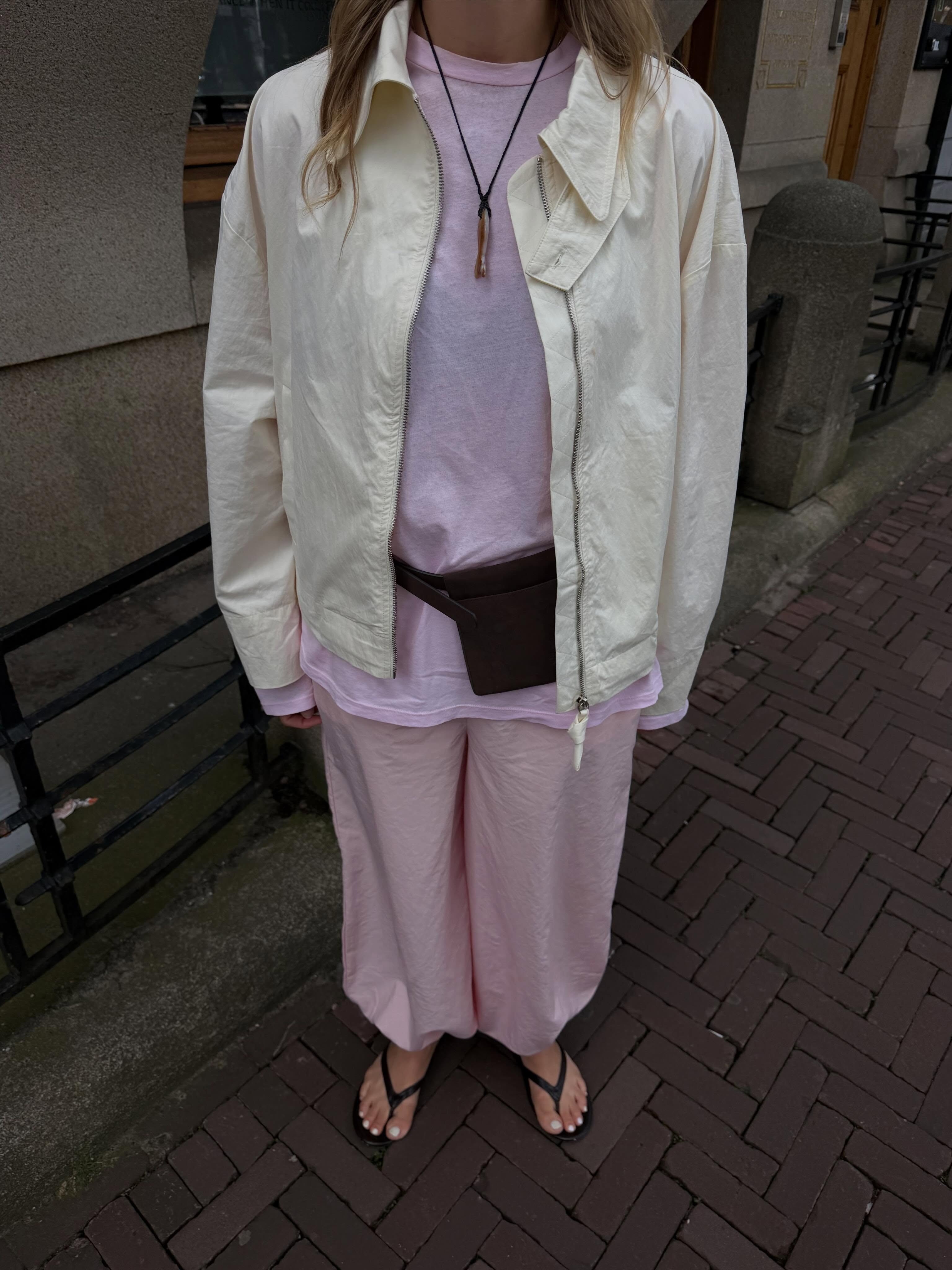 Influencer @holliemercedes wears a fish necklace with a pink t-shirt and trousers.