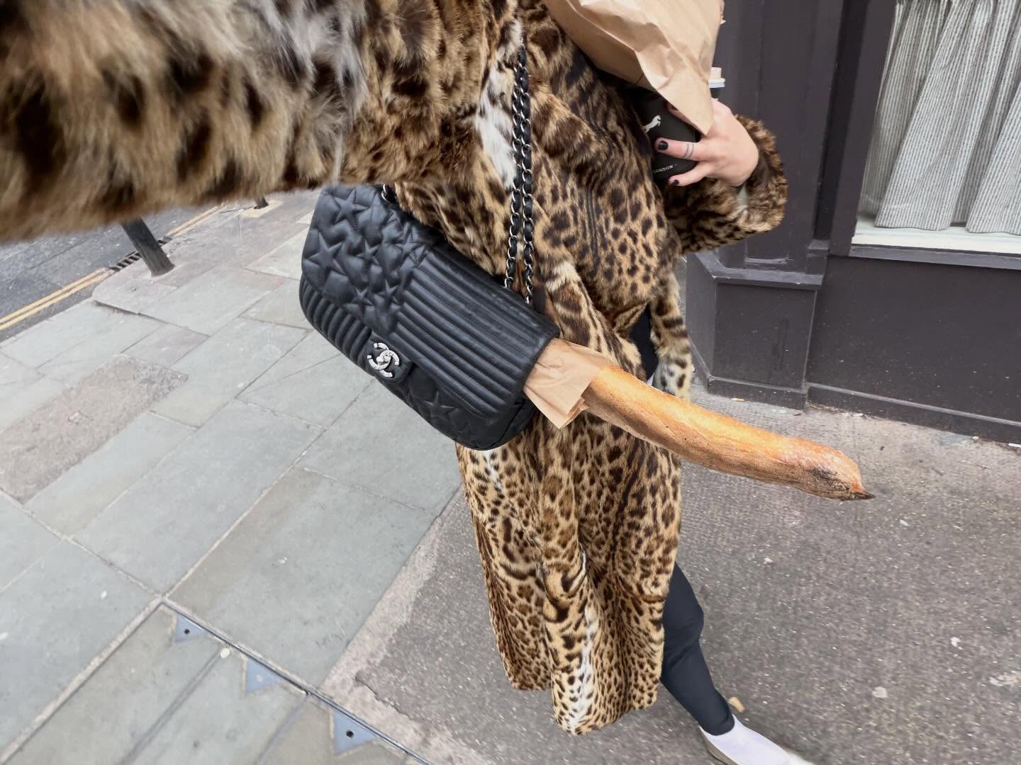 Camille Charriere's black Chanel bag with a baguette and leopard coat.