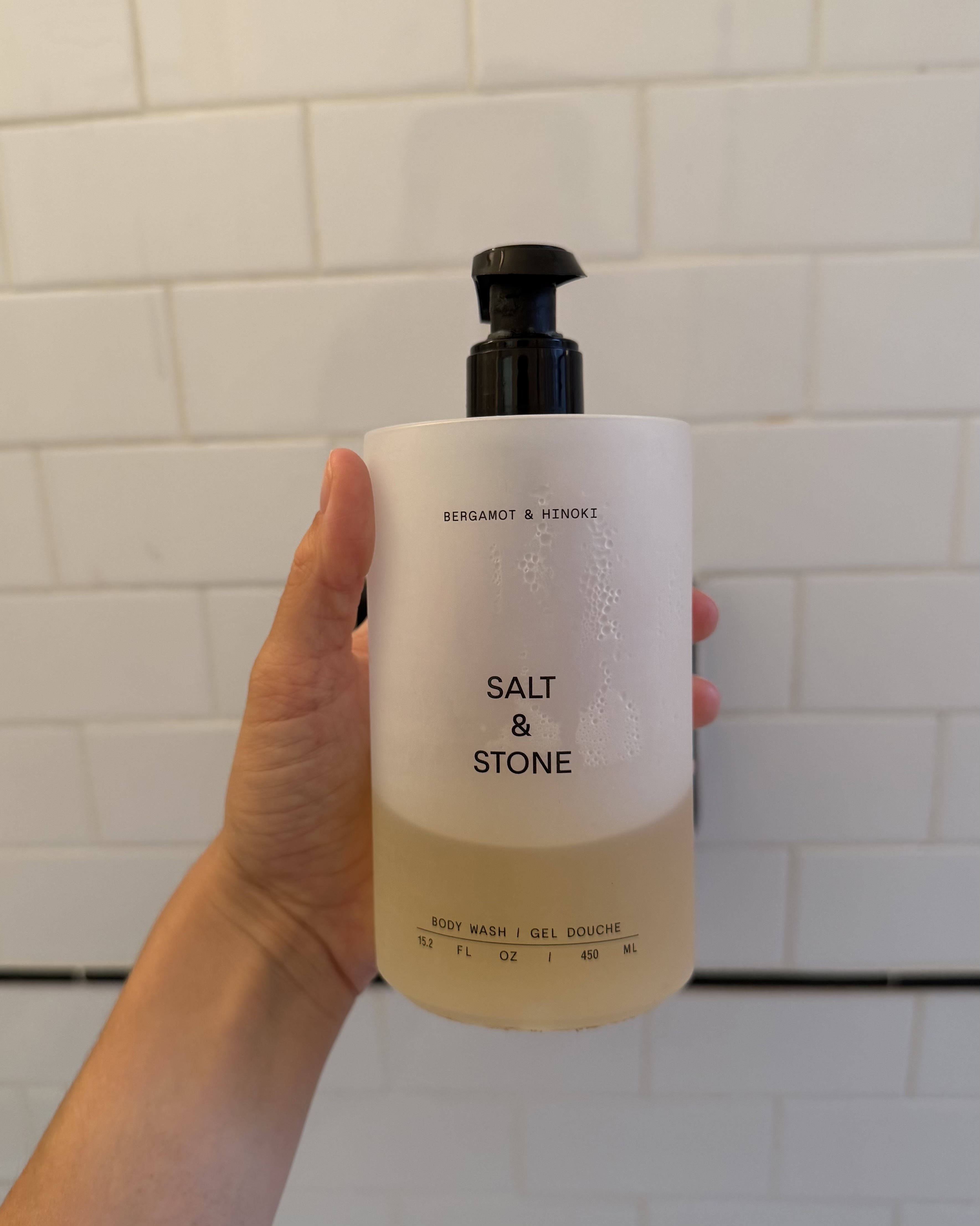 An image of associate beauty editor Alyssa Brascia holding the Salt & Stone Bergamot and Hinoki Body Wash.