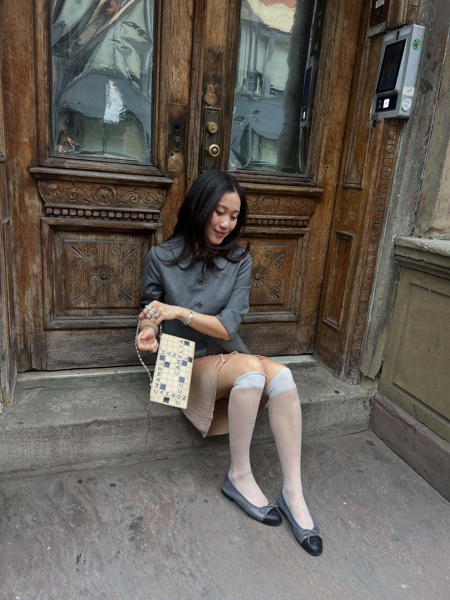 An image of @vivianyrl  wearing a pair of two-toned ballet flats with a champagne coloured silk skirt and a grey jacket.
