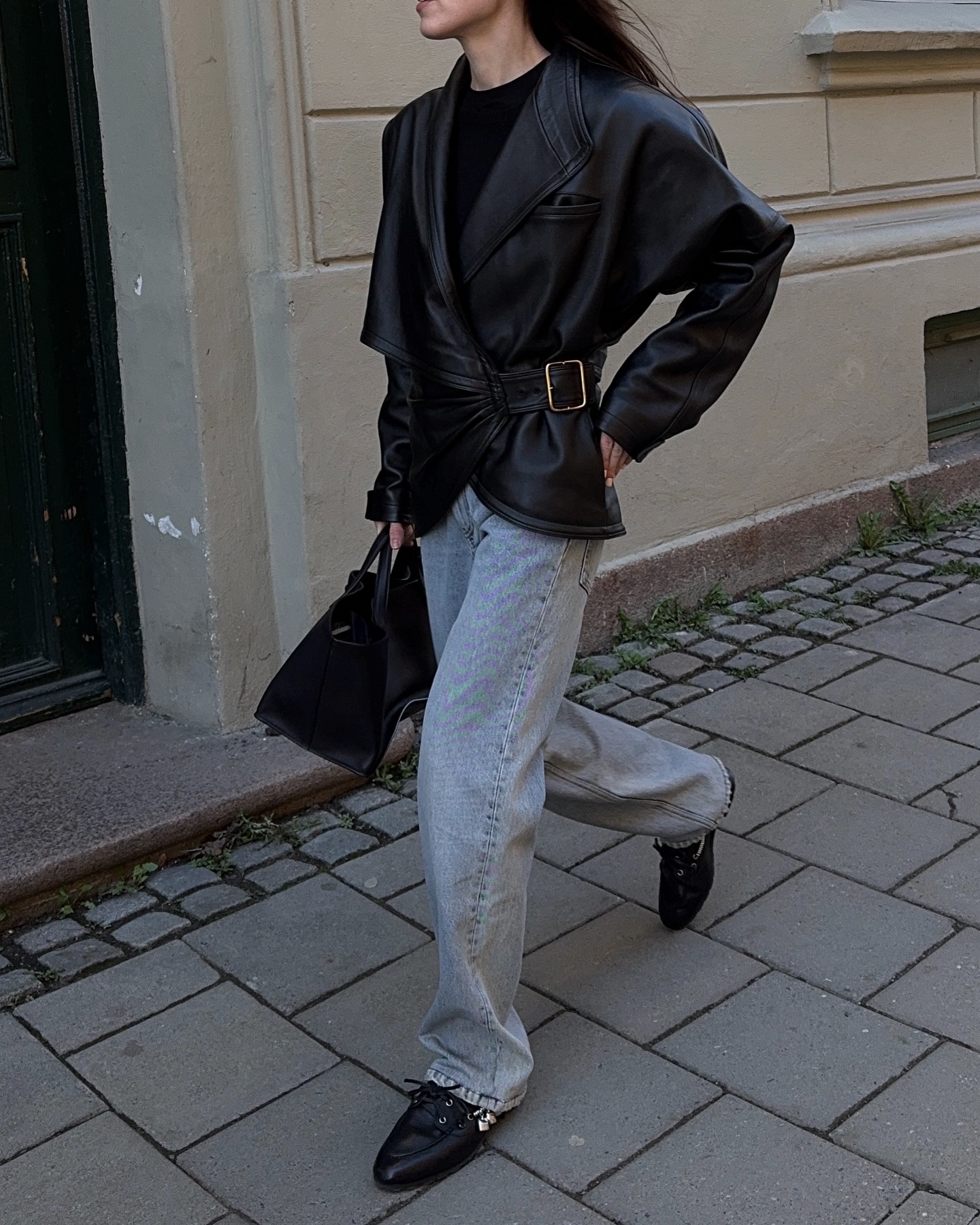 An image of @annabelrosendahl wearing blue jeans with a black leather jacket and deck shoe trainers from Miu Miu.