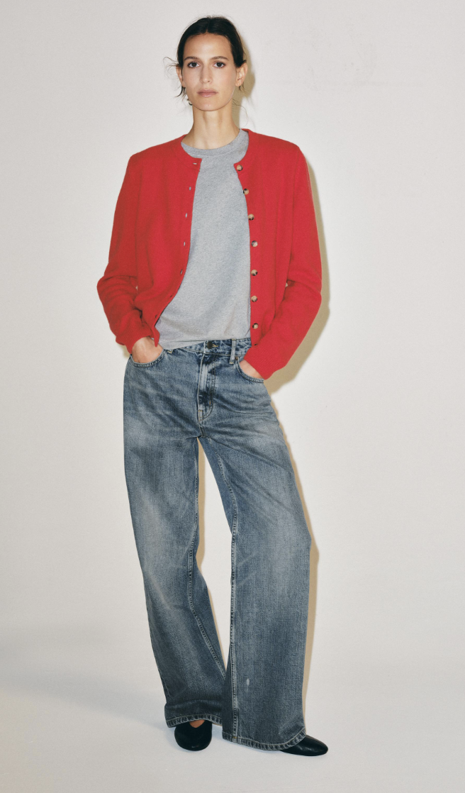 Zara early autumn colour trends. The model wears a red cardigan, with a grey t-shirt, washed blue jeans and black ballet flats.
