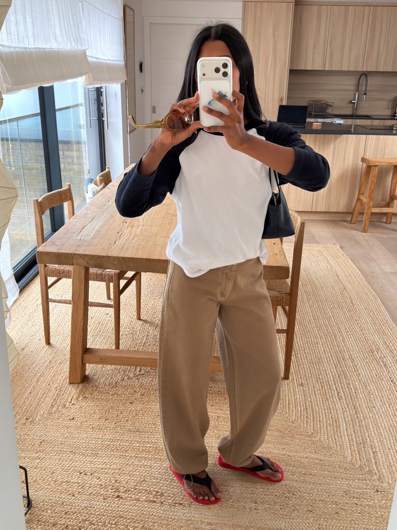 Influencer Monikh wearing a raglan long sleeve t-shirt, beige jeans and flip flops.