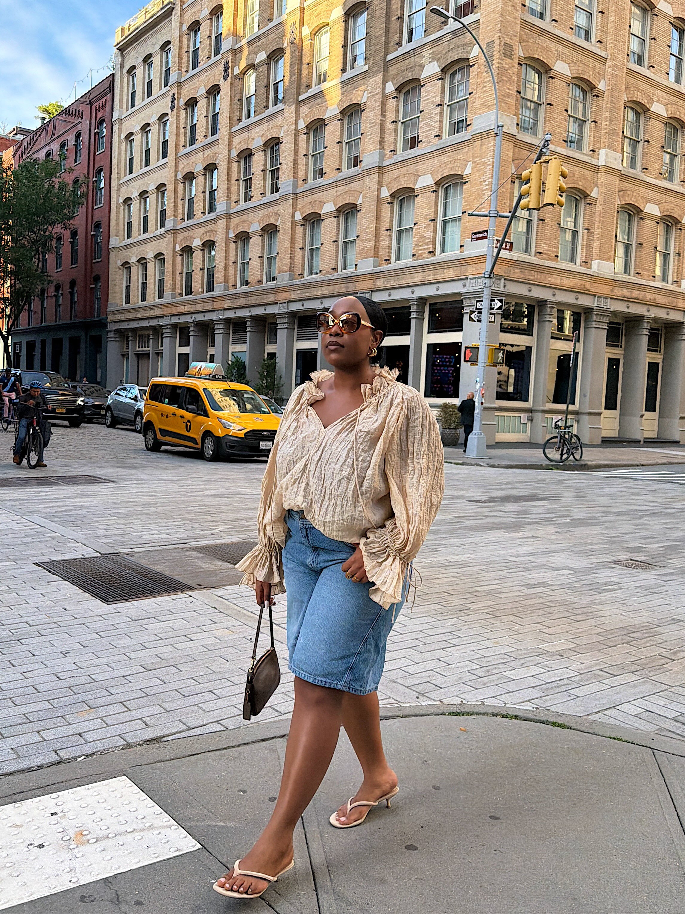 A woman wearing long, loose denim shorts in summer 2026.