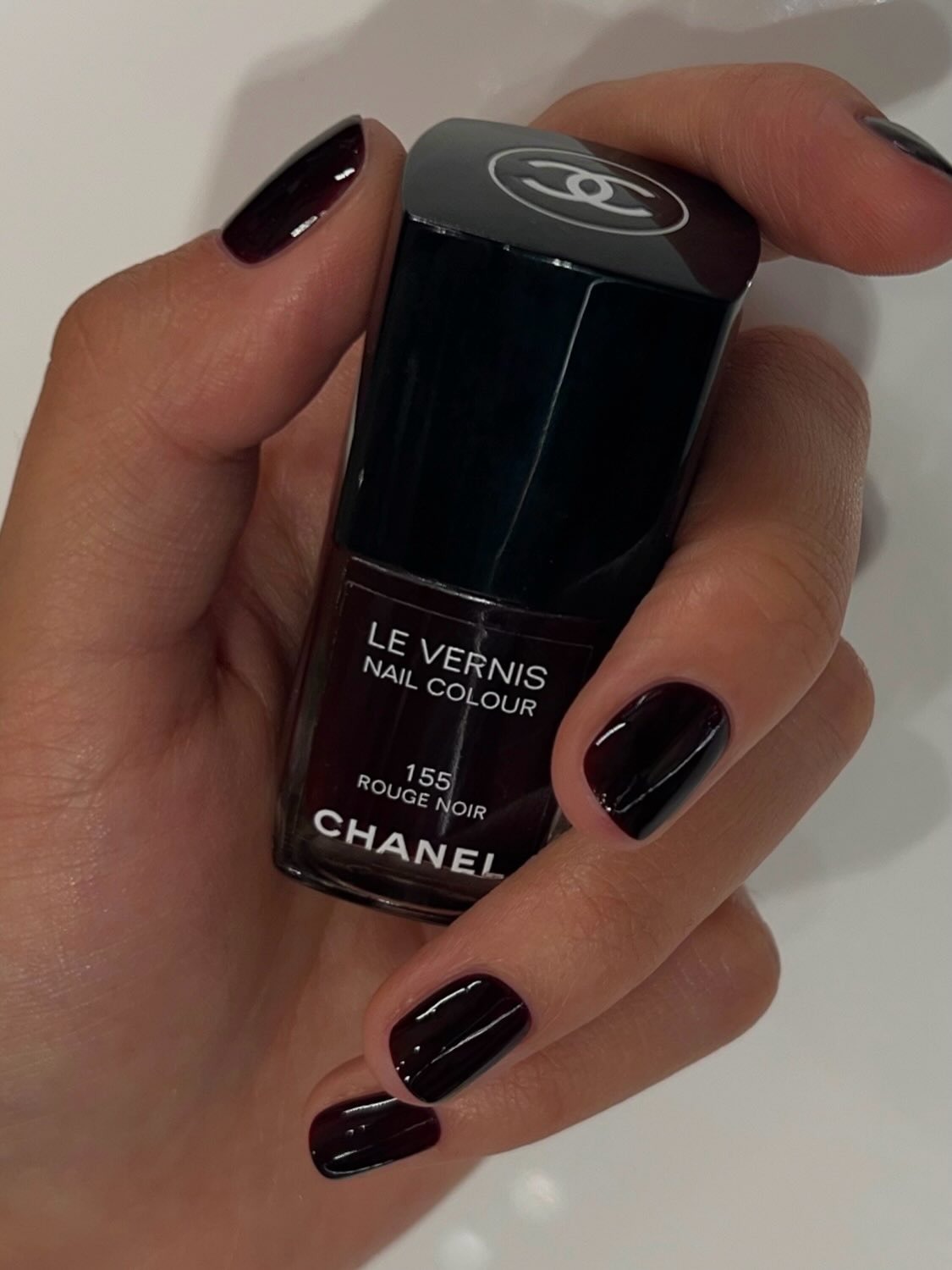 A picture of a woman with a rouge noir manicure holding the Chanel Rouge Noir nail polish