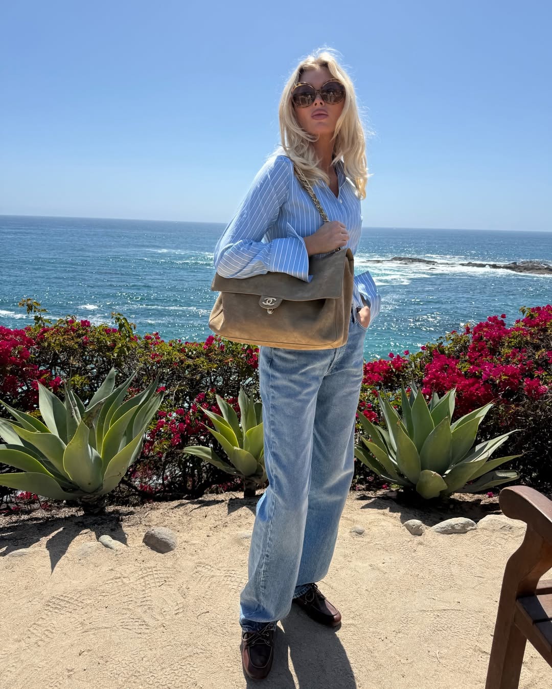 Model Elsa Hosk wears a blue button down shirt with blue jeans, boat shoes and a Chanel tote bag.