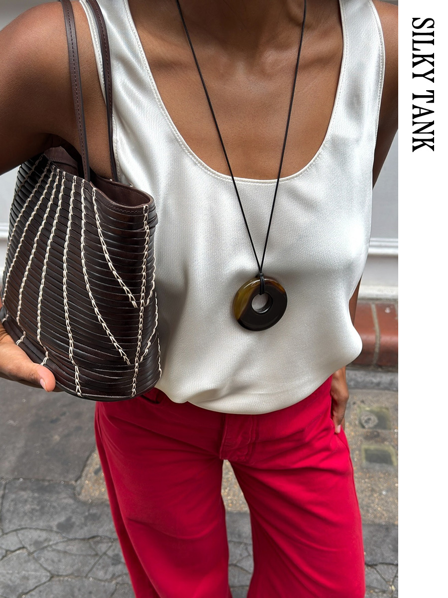 Woman wearing a silk tank and red pants with a woven The Row tote
