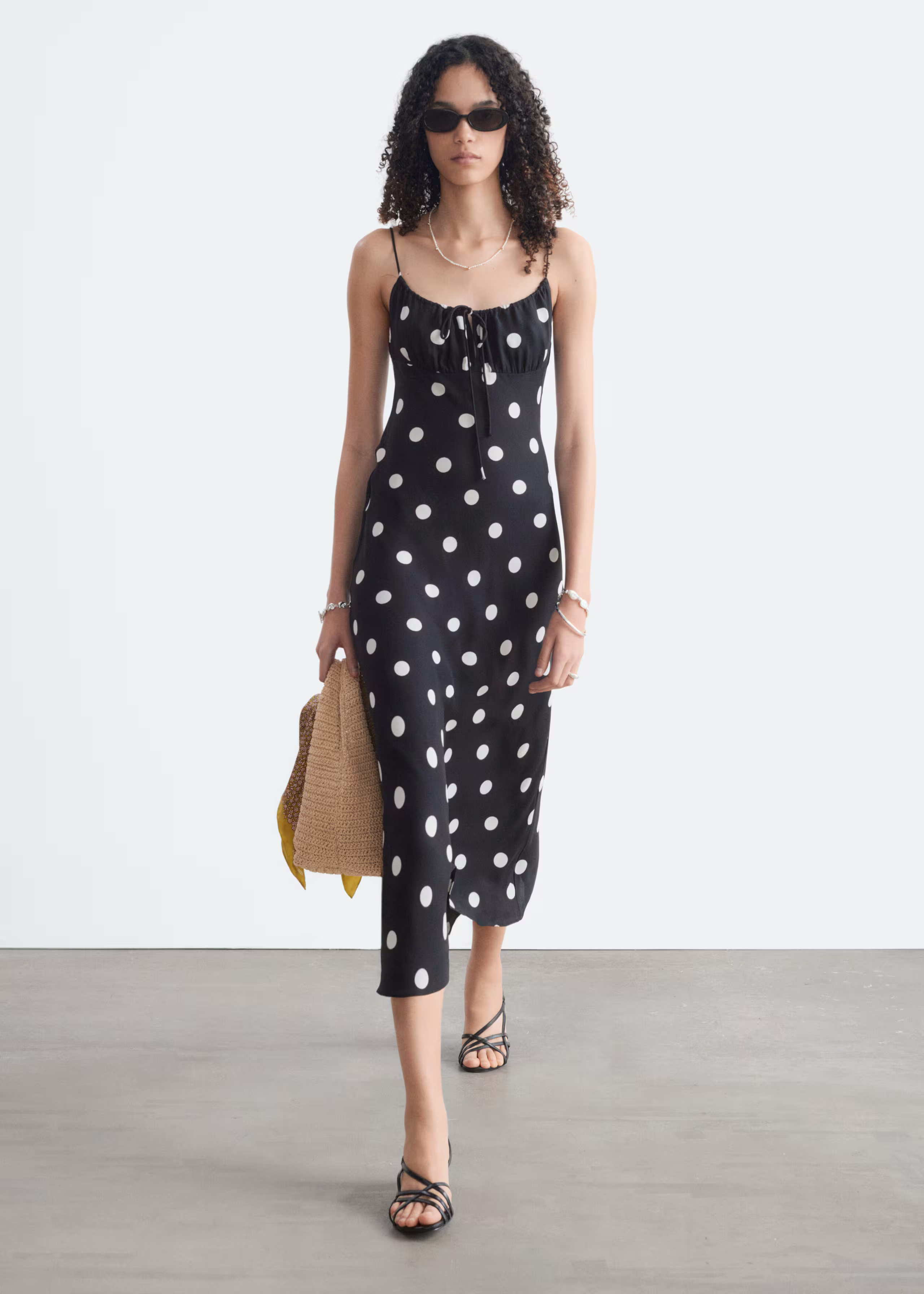 A model wearsa black & Other Stories polkadot dress.