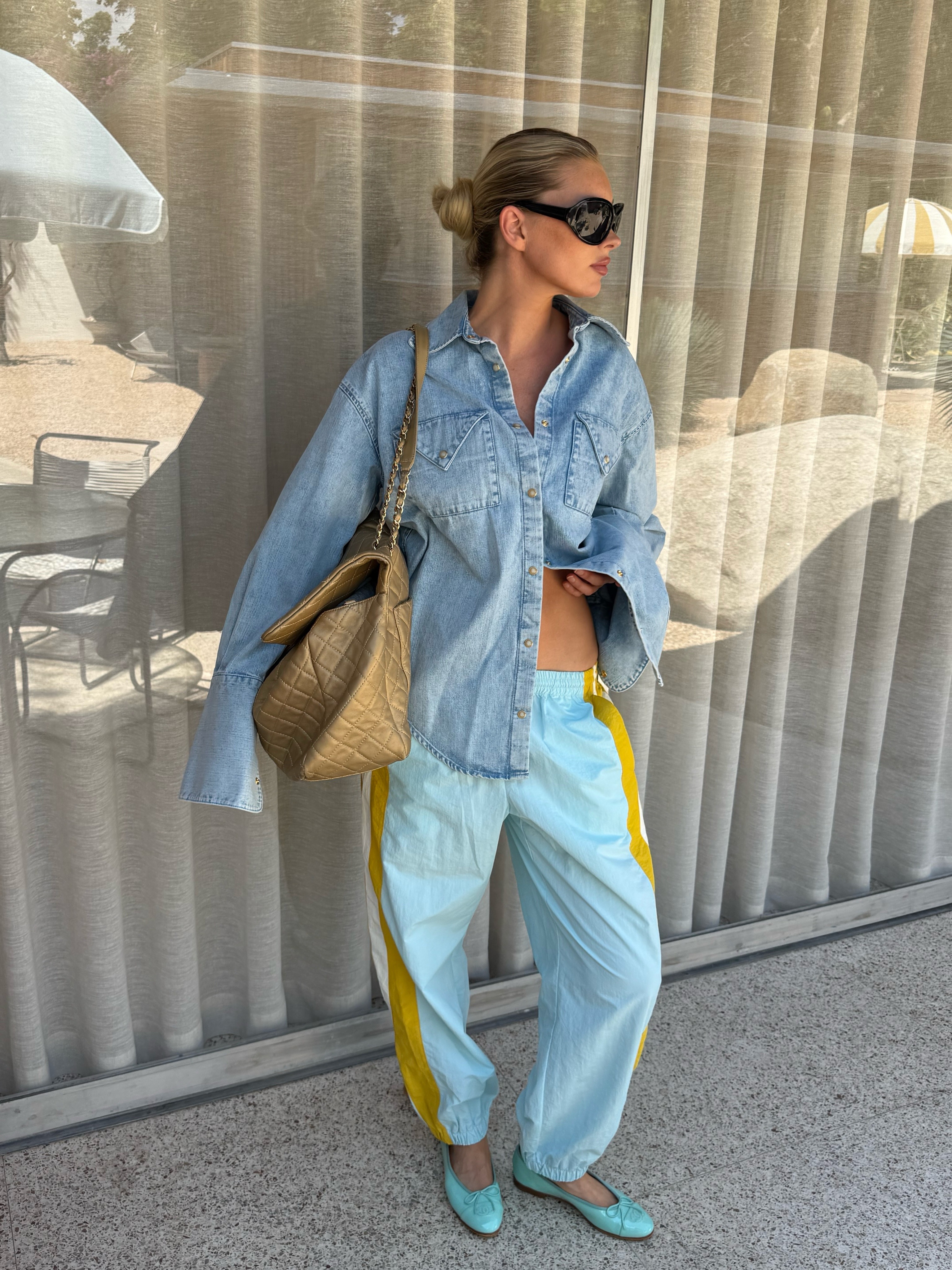 Elsa Hosk wearing a denim shirt, light-blue balloon track pants, a Chanel bag, and Chanel aqua ballet flats