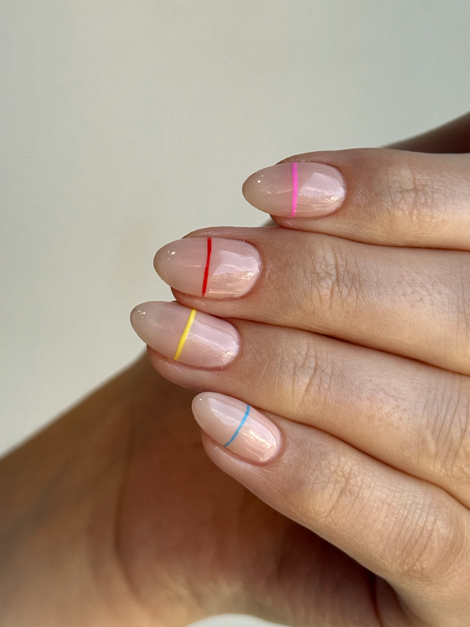 Nude nails with a single colourful band across the middle of each one.