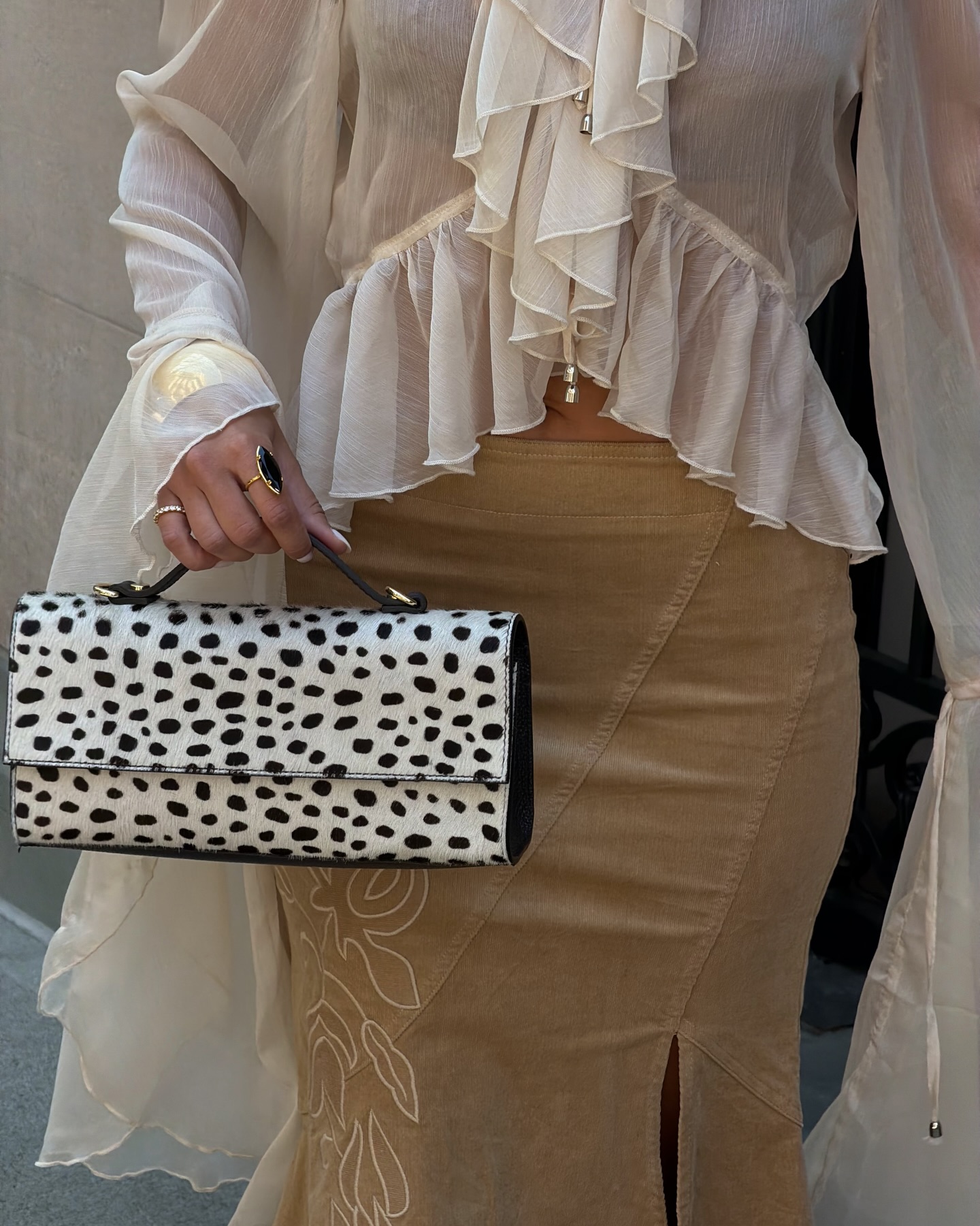 A close-up image of an influencer's hand holding a Dalmatian handbag in New York City
