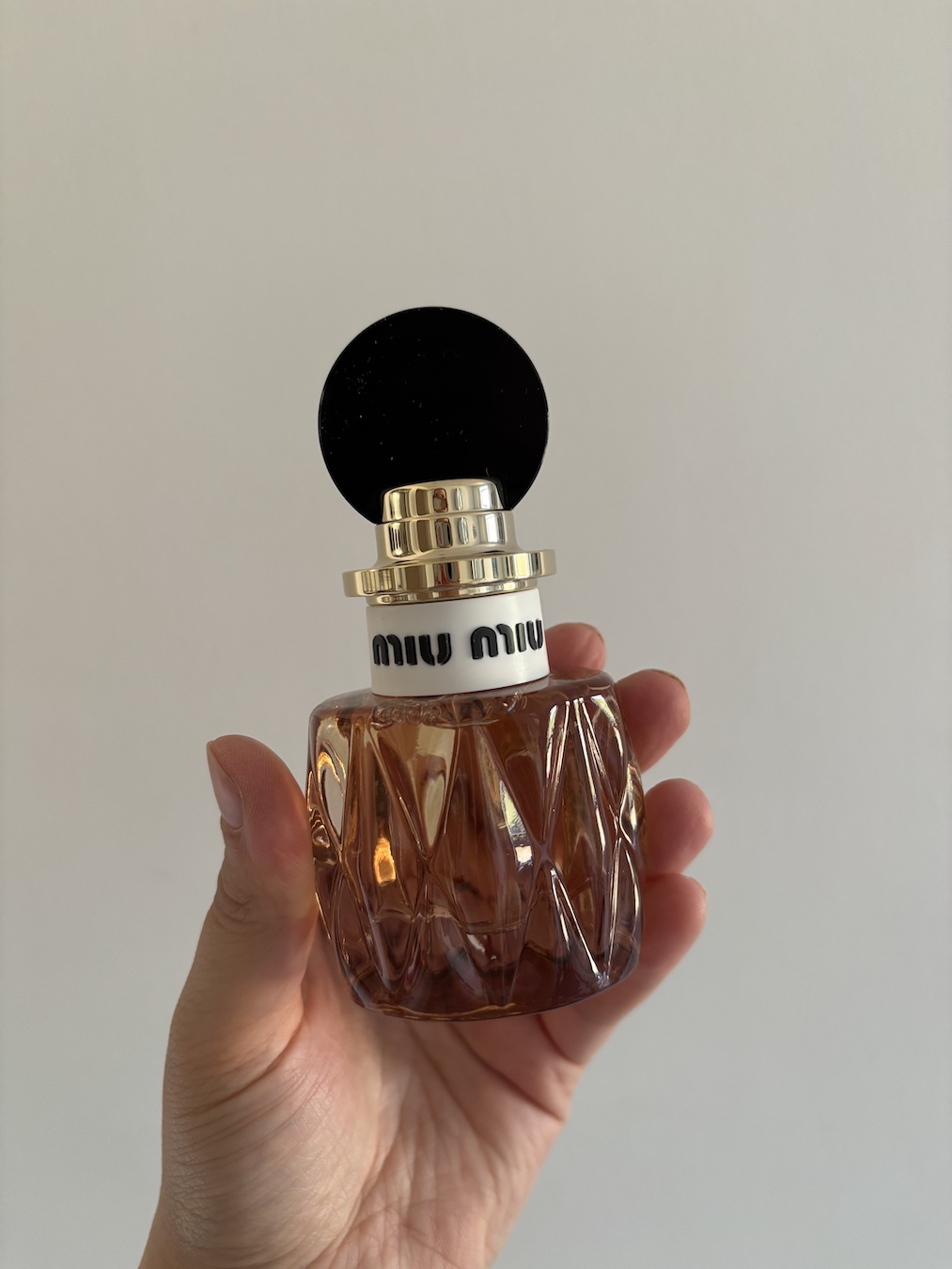 Mica Ricketts holding bottle of Miu Miu Miutine perfume