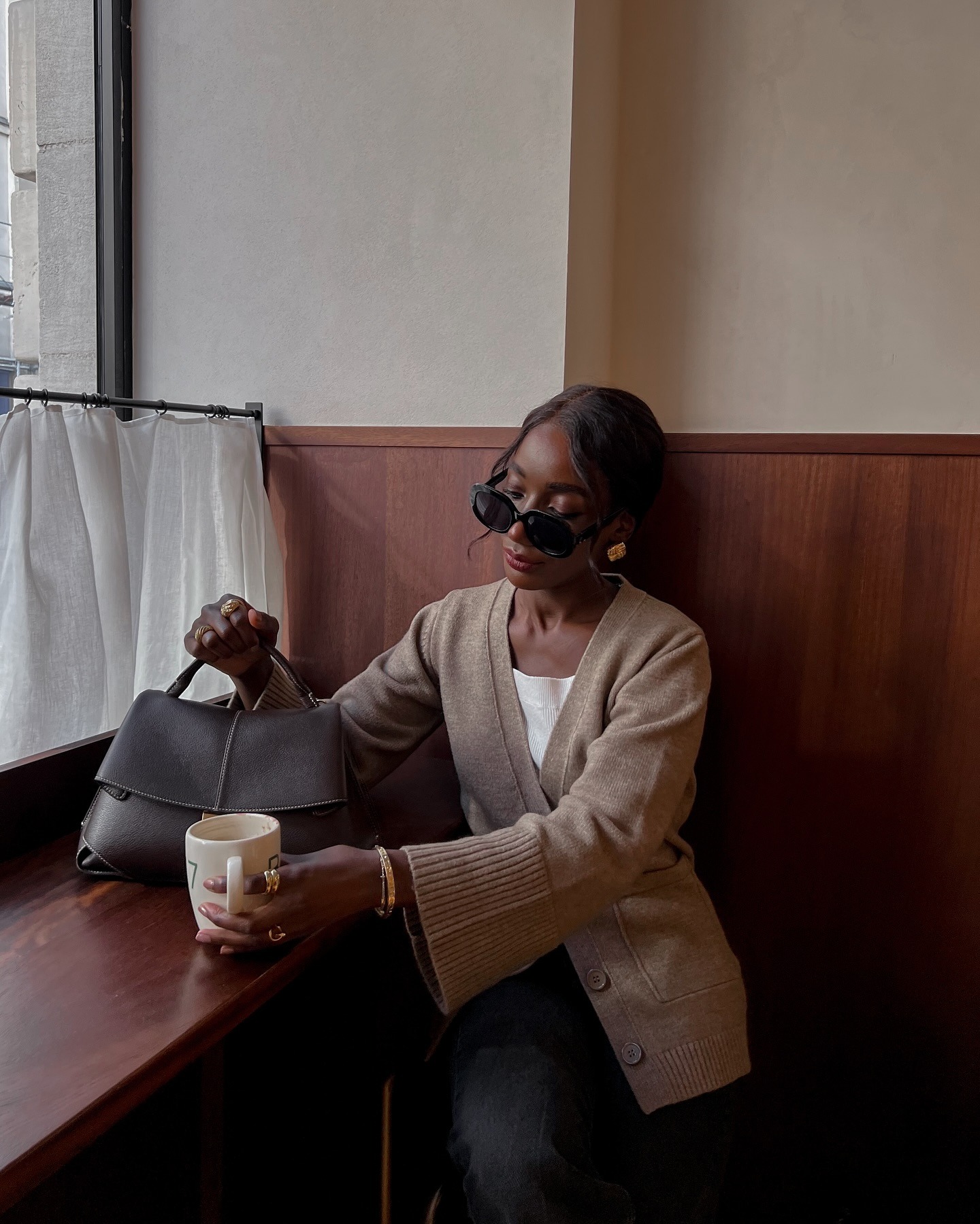 Woman wears cardigan, white top, sunglasses