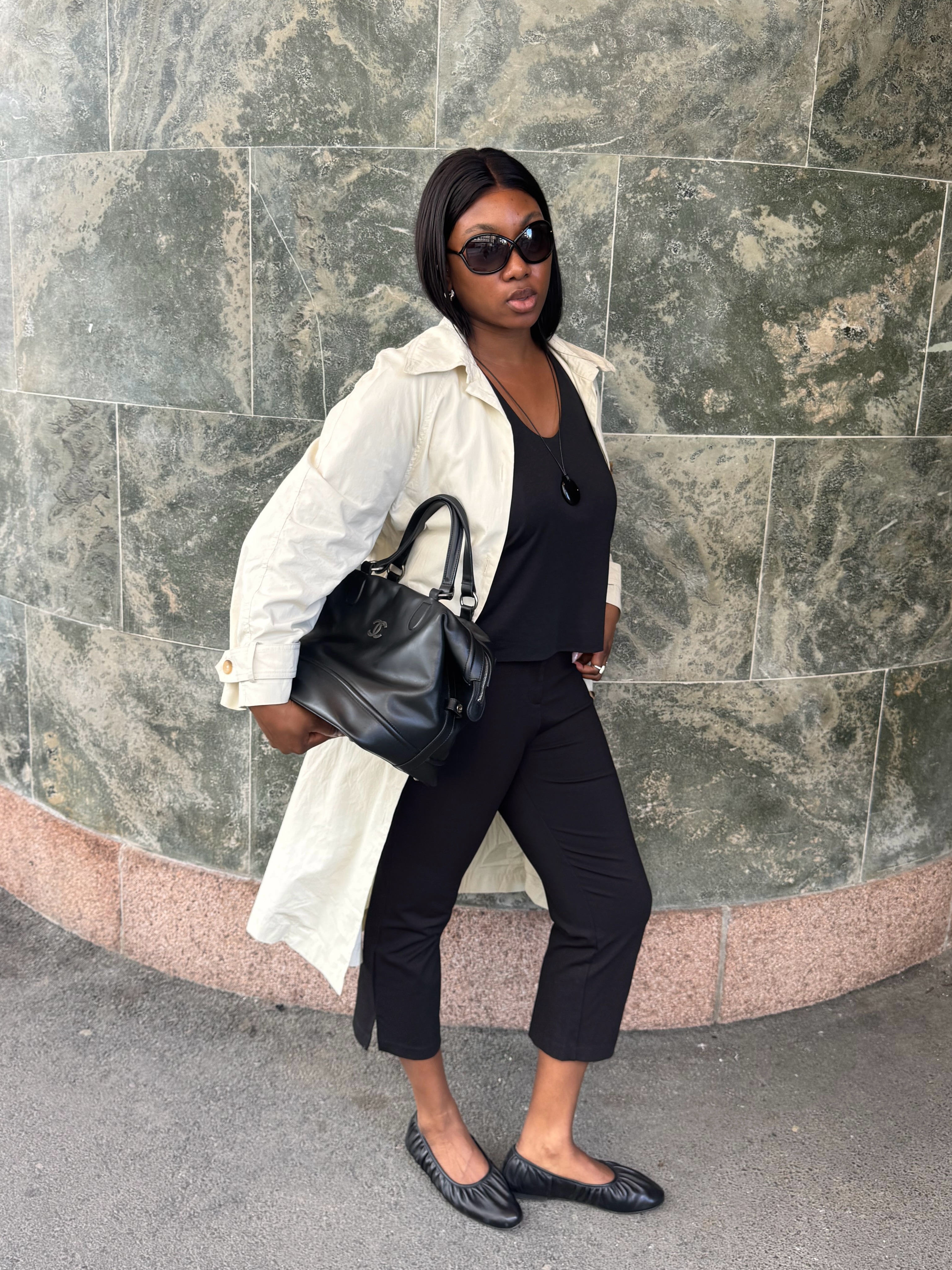 Woman in capri pants, a trench, and black ballet flats