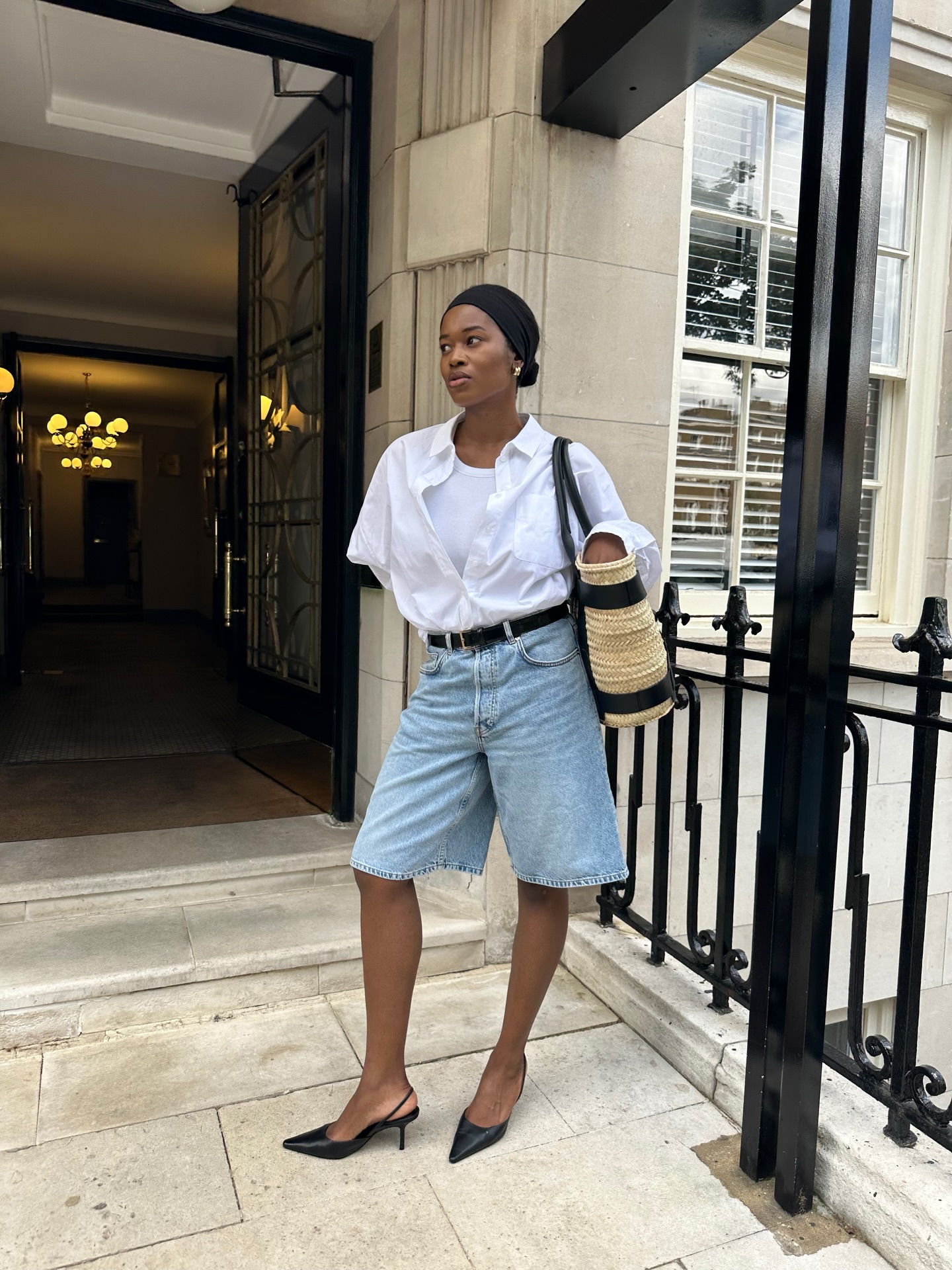 A woman wearing long, loose denim shorts in summer 2026.
