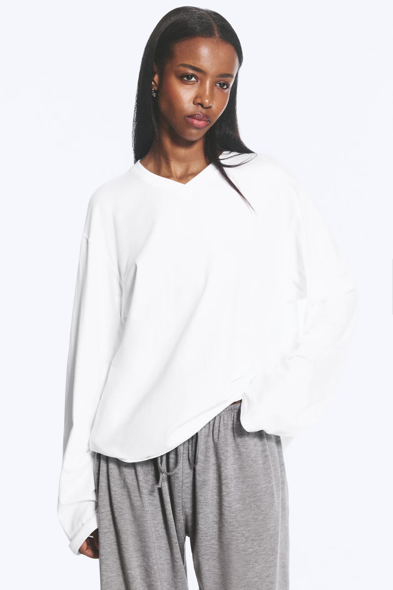 A model wears a white v-neck long sleeve Weekday t-shirt.