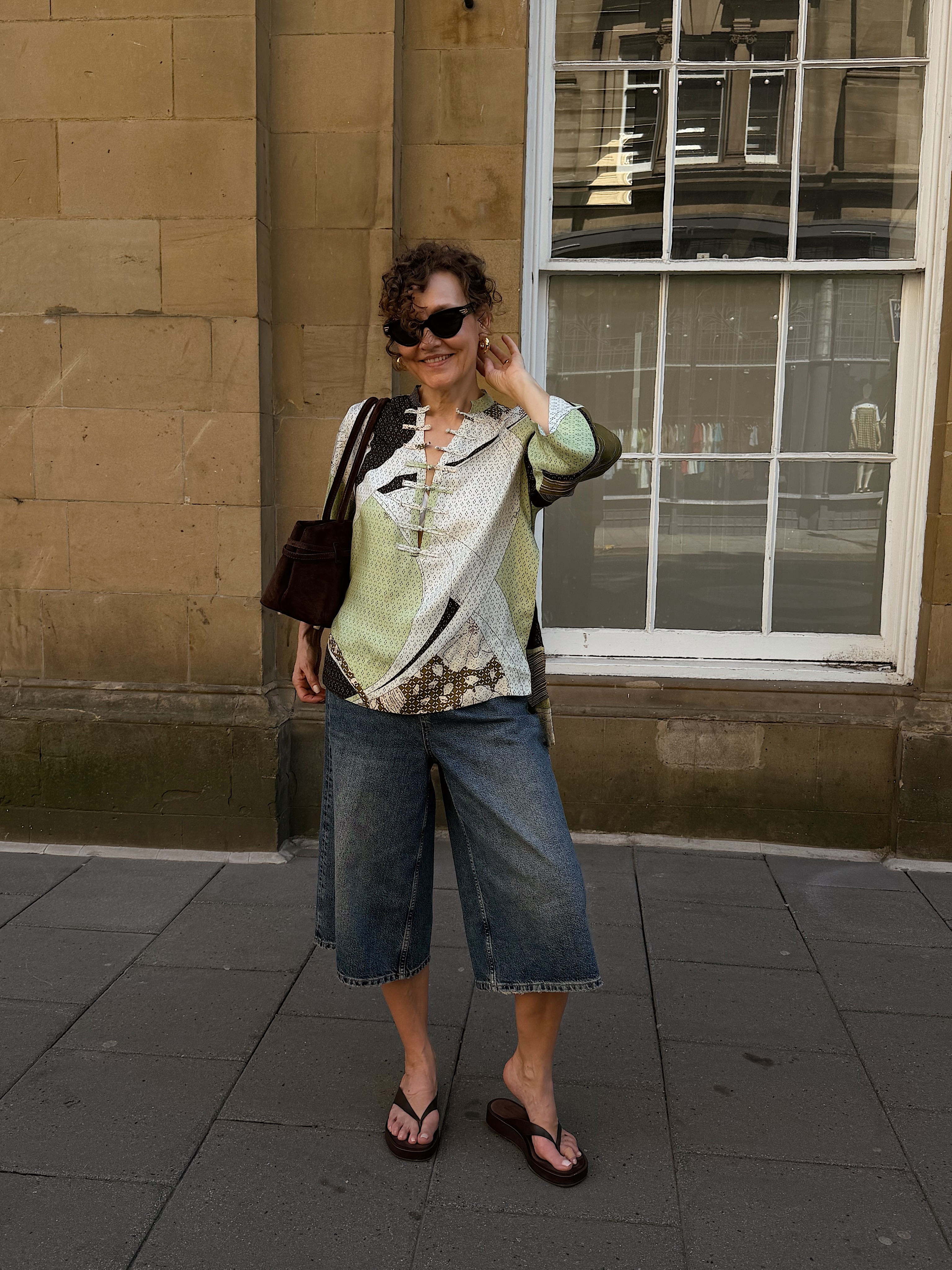 A woman wearing long, loose denim shorts in summer 2026.