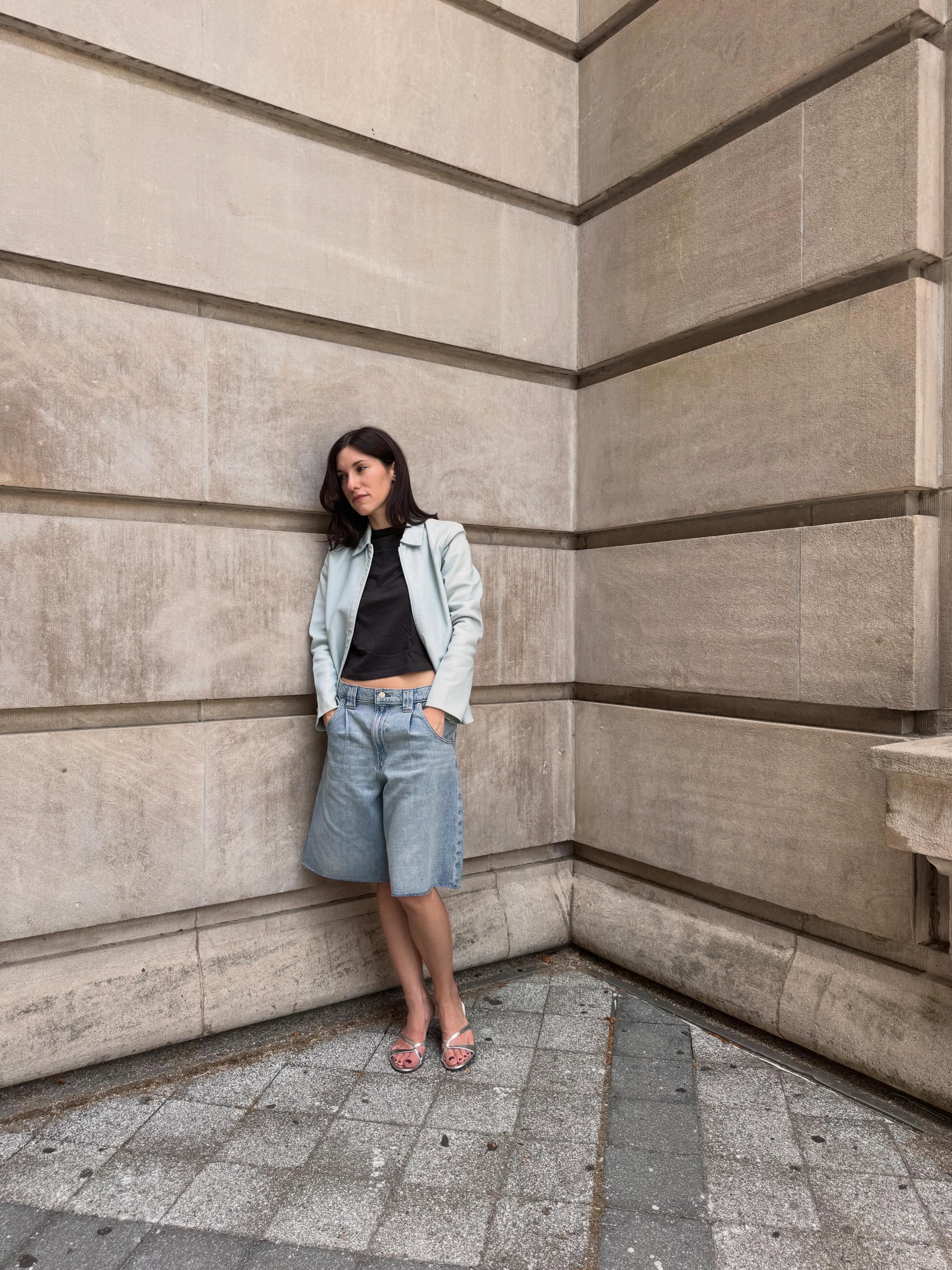 A woman wearing long, loose denim shorts in summer 2026.