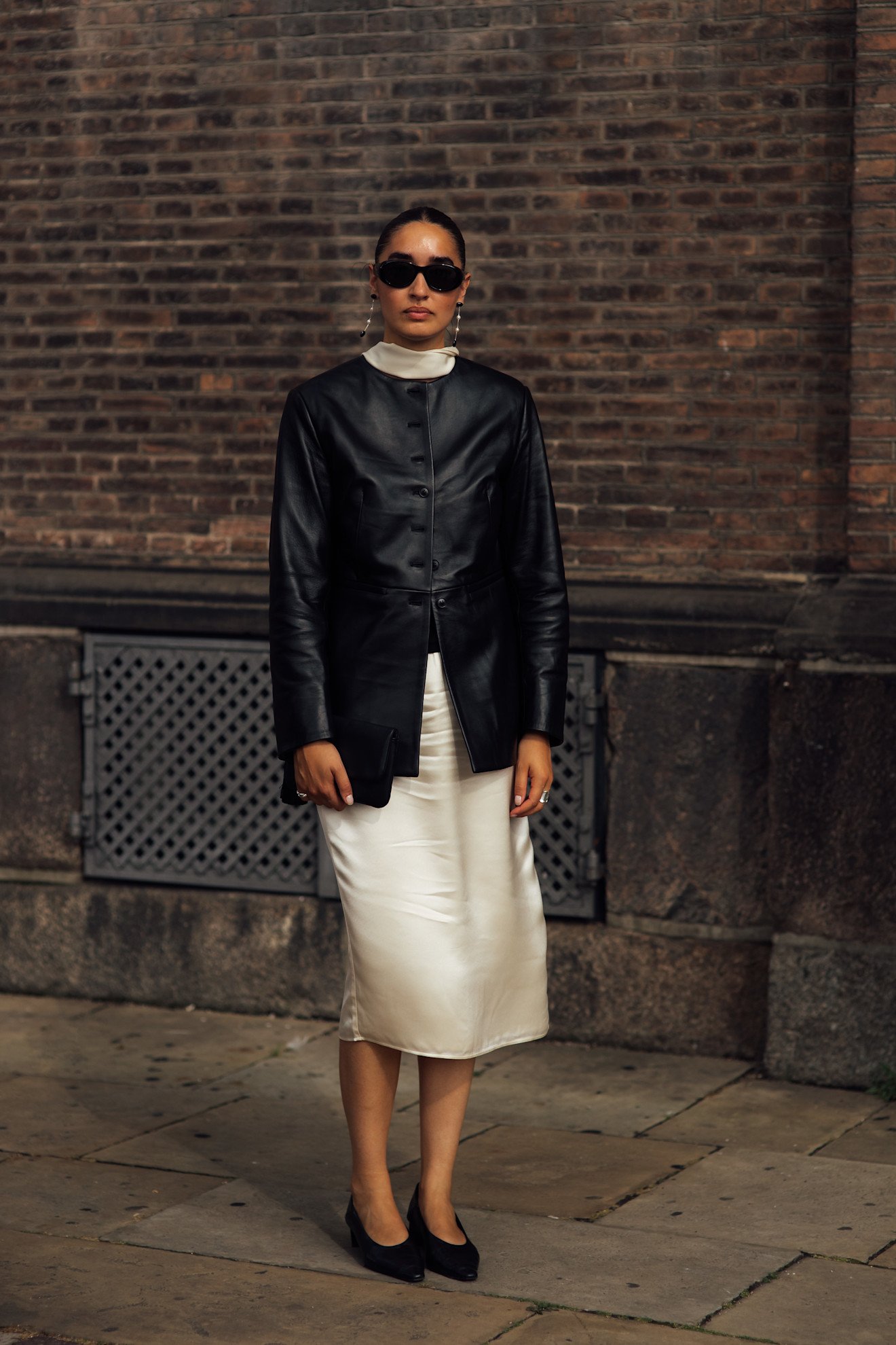 A woman wearing a black leather jacket and a satin skirt