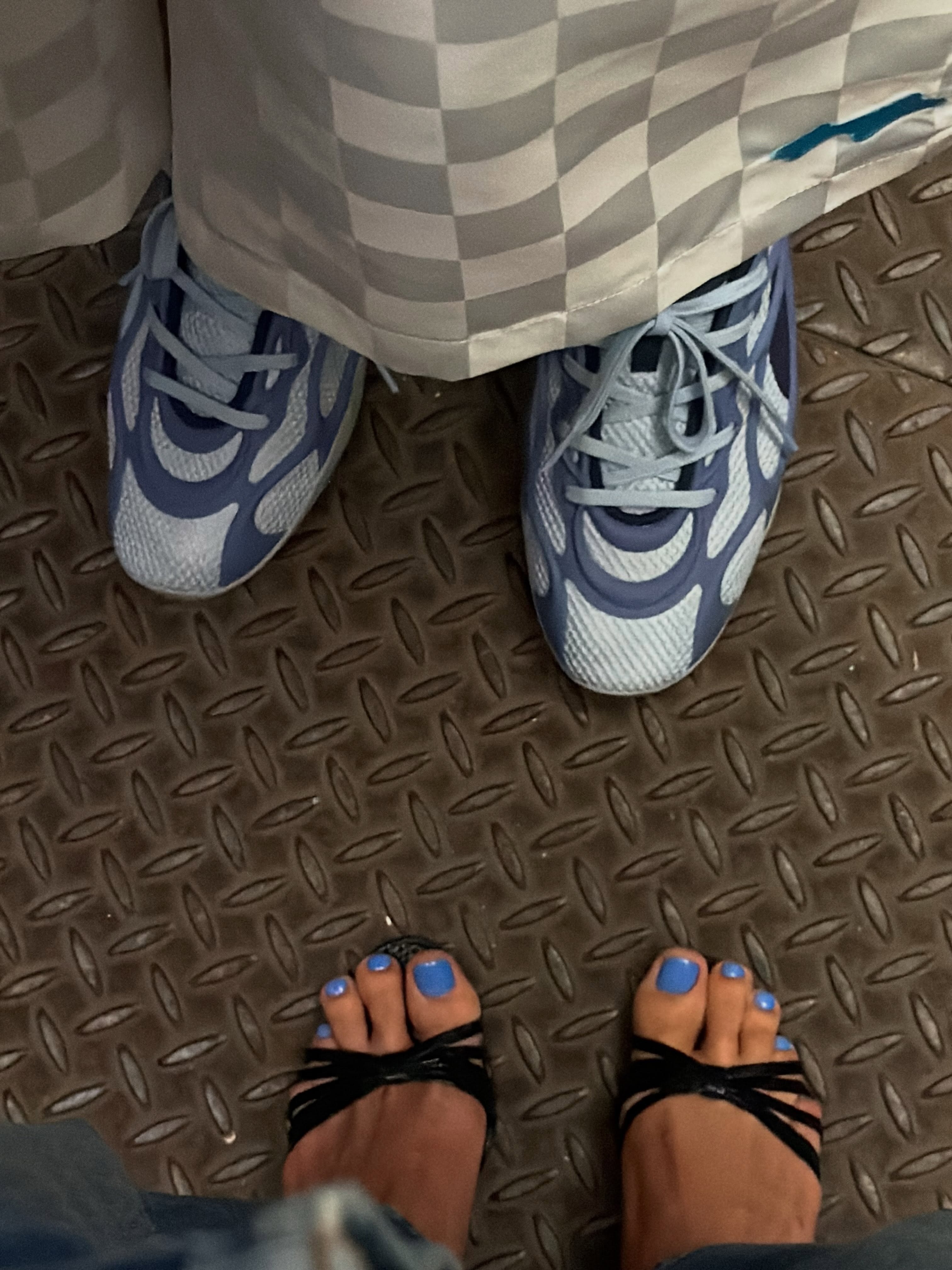Hailey Bieber wearing black sandals with a blue pedicure