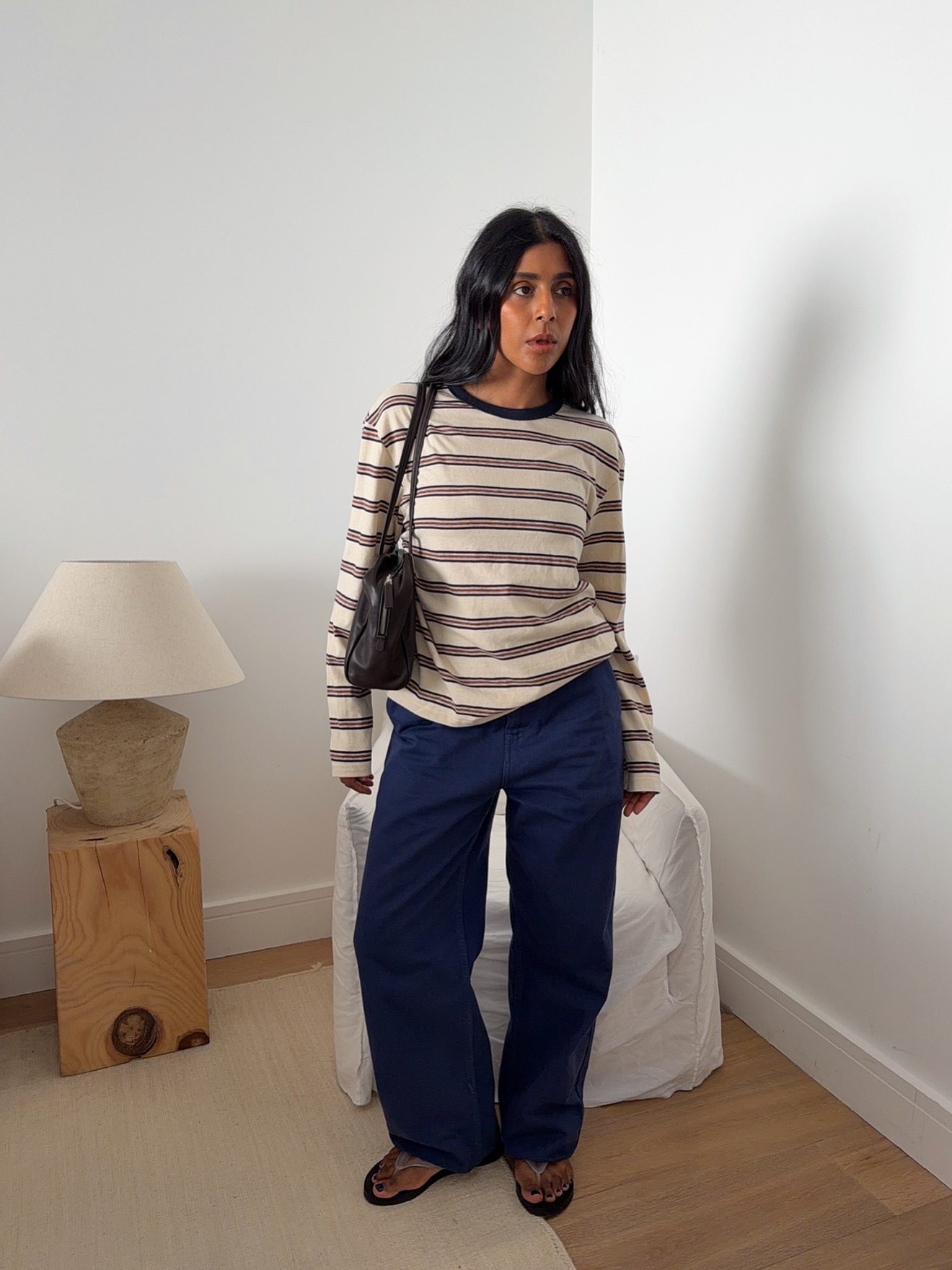 @monikh in a striped longsleeve T-shirt, blue pants, and flip flops.