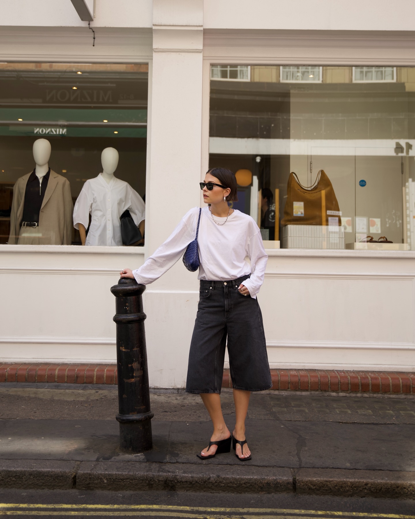 A woman wearing long, loose denim shorts in summer 2026.
