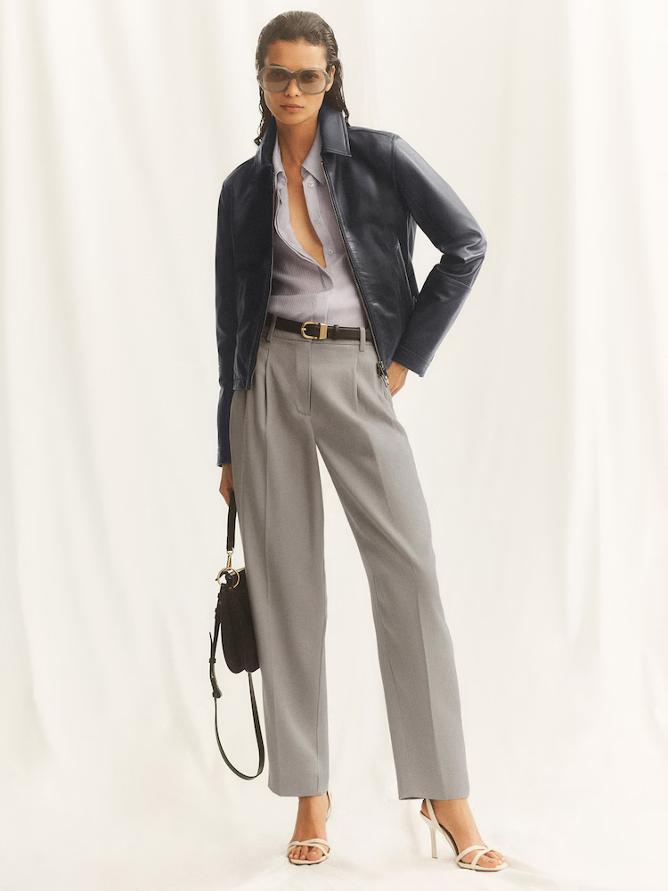 A model wearing a pair of grey tailored Reiss trousers.