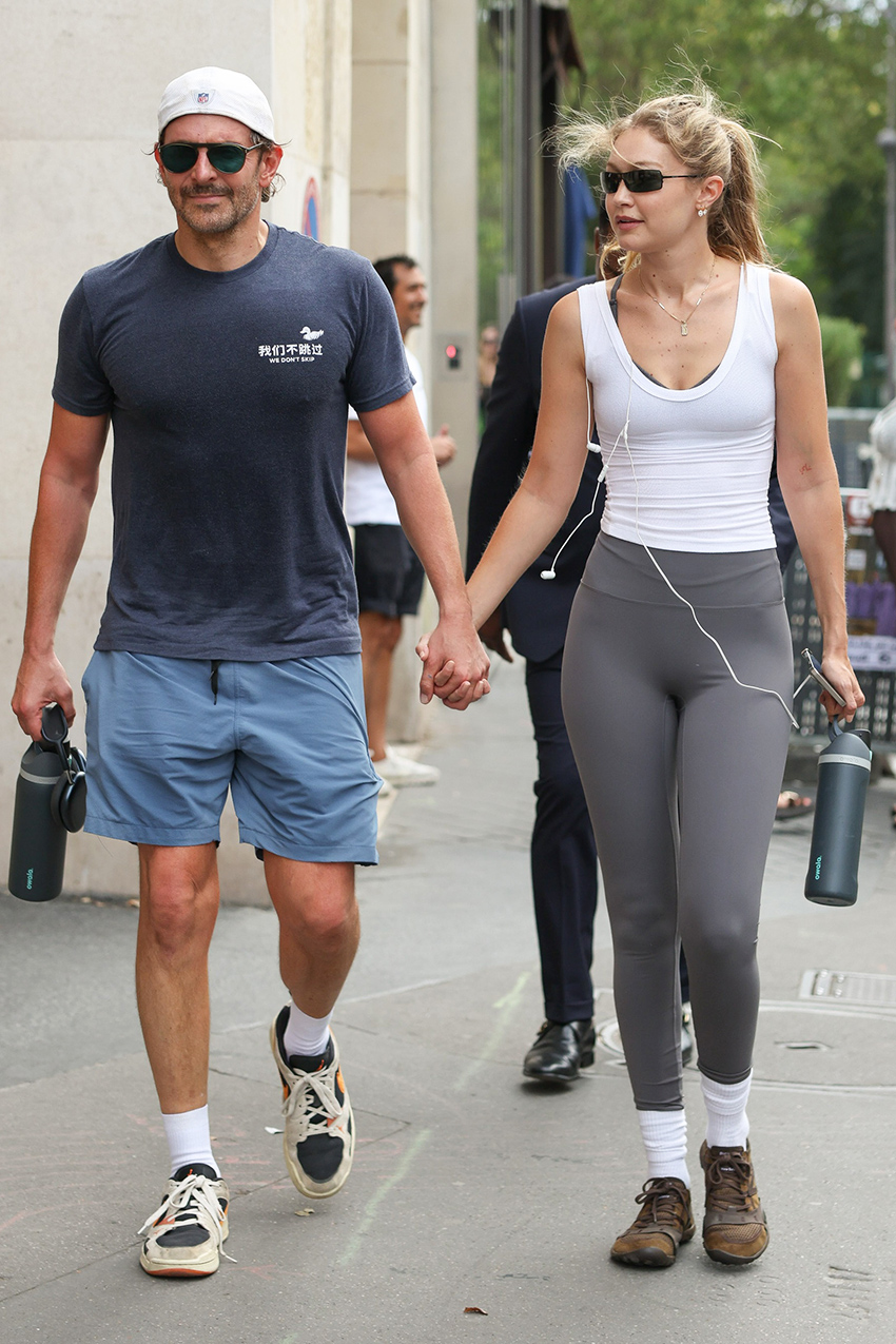 Gigi Hadid with Bradley Cooper in Paris, wearing a white tank top, gray leggings, and brown suede New Balance sneakers