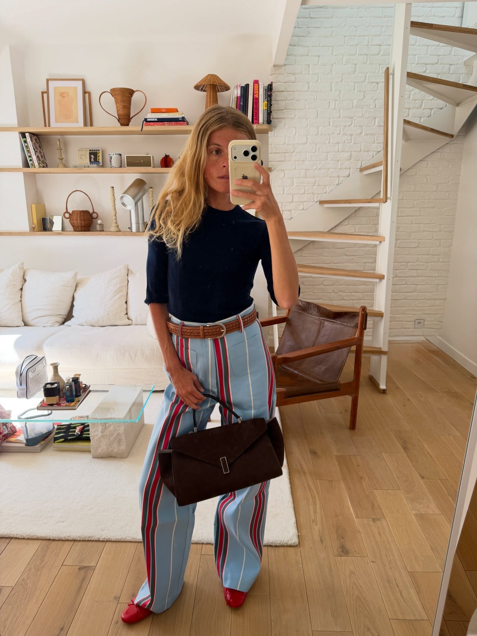 An image of @alicepilate wearing stripe jeans with red ballet flats and a three-quarter-length shirt.