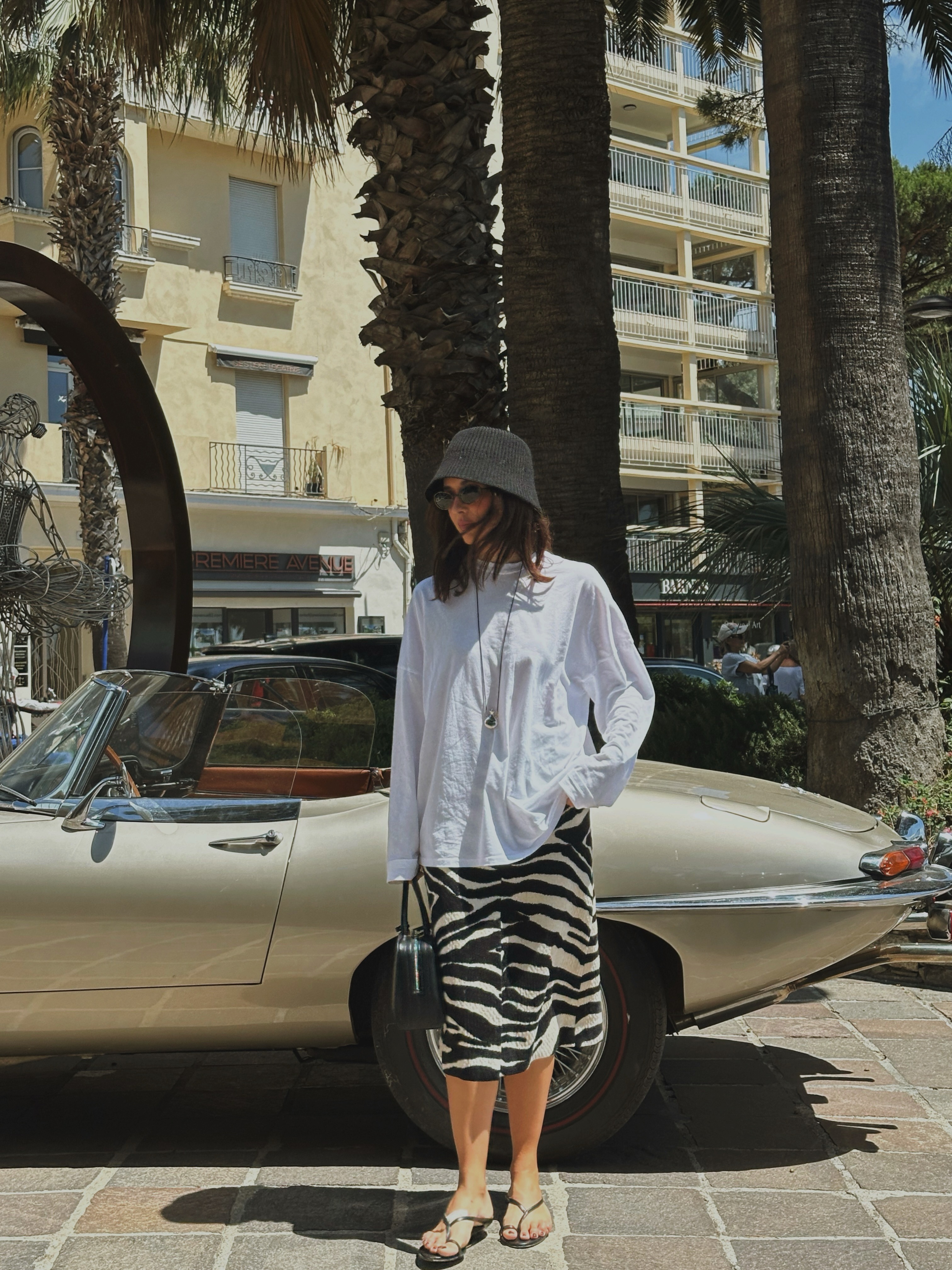 Influencer @deborabrosa wears a baggy long-sleeve t-shirt with a knee-length skirt and flip-flops.