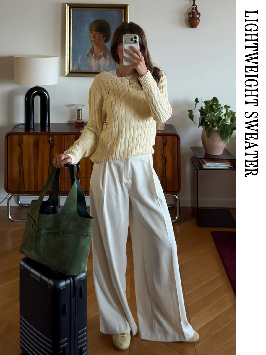 Travel outfit that includes a yellow sweater, white trousers , and ballet flats