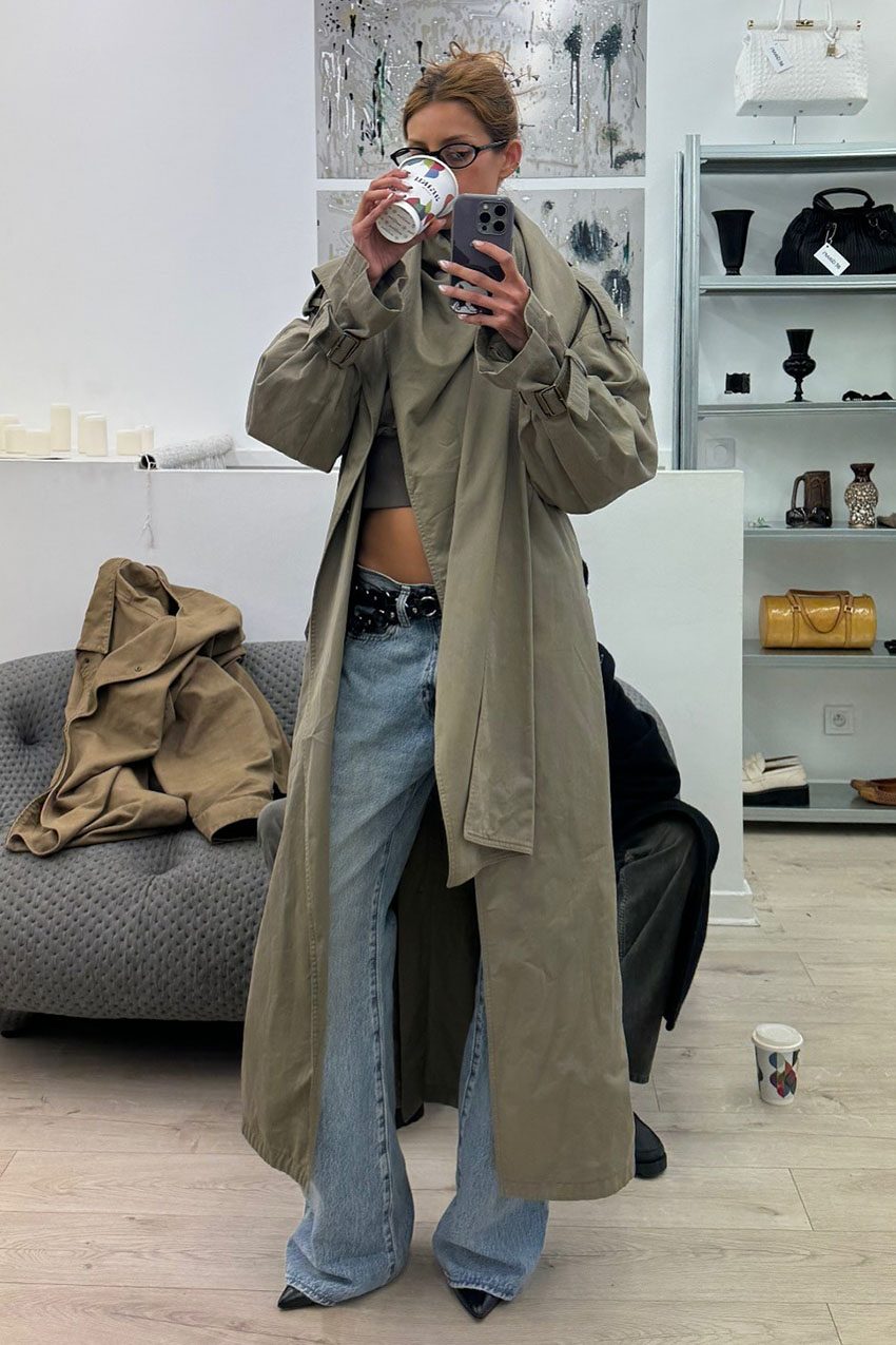 a woman wearing a trench coat, blue low-rise jeans, and pointed toe heels