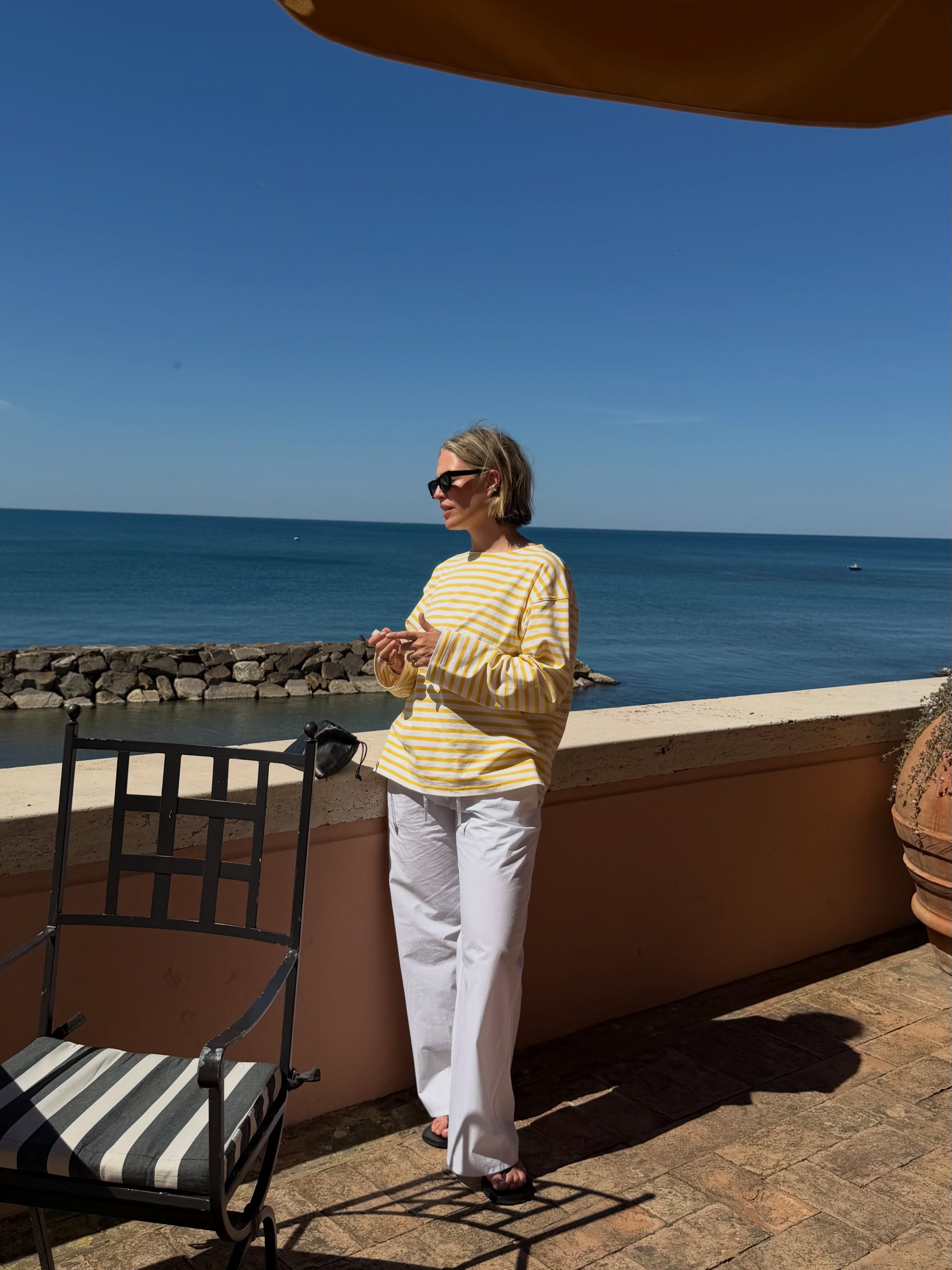 An image of @alexisforeman wearing a striped shirt with white jeans and flip-flops.