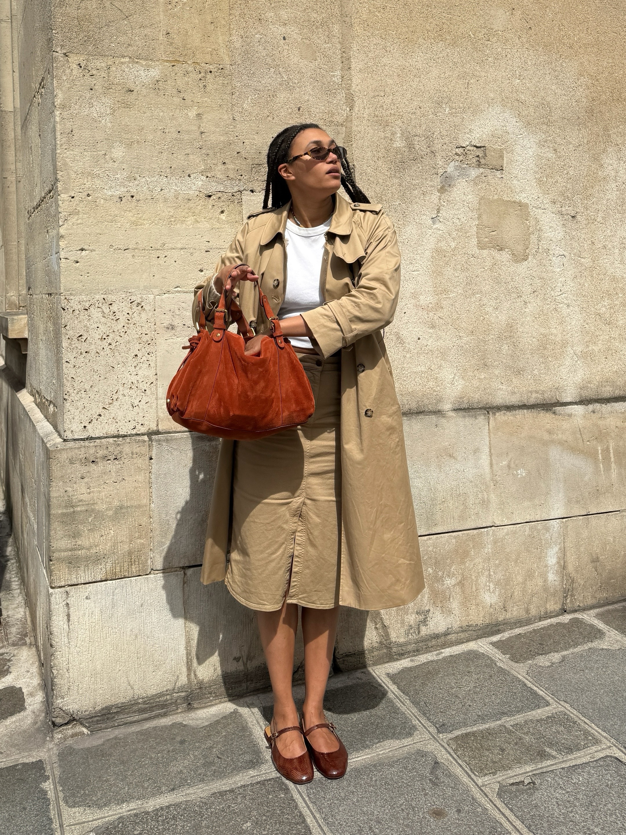 lena farl wears a trench coat, white tee, camel skirt and ballet mary janes
