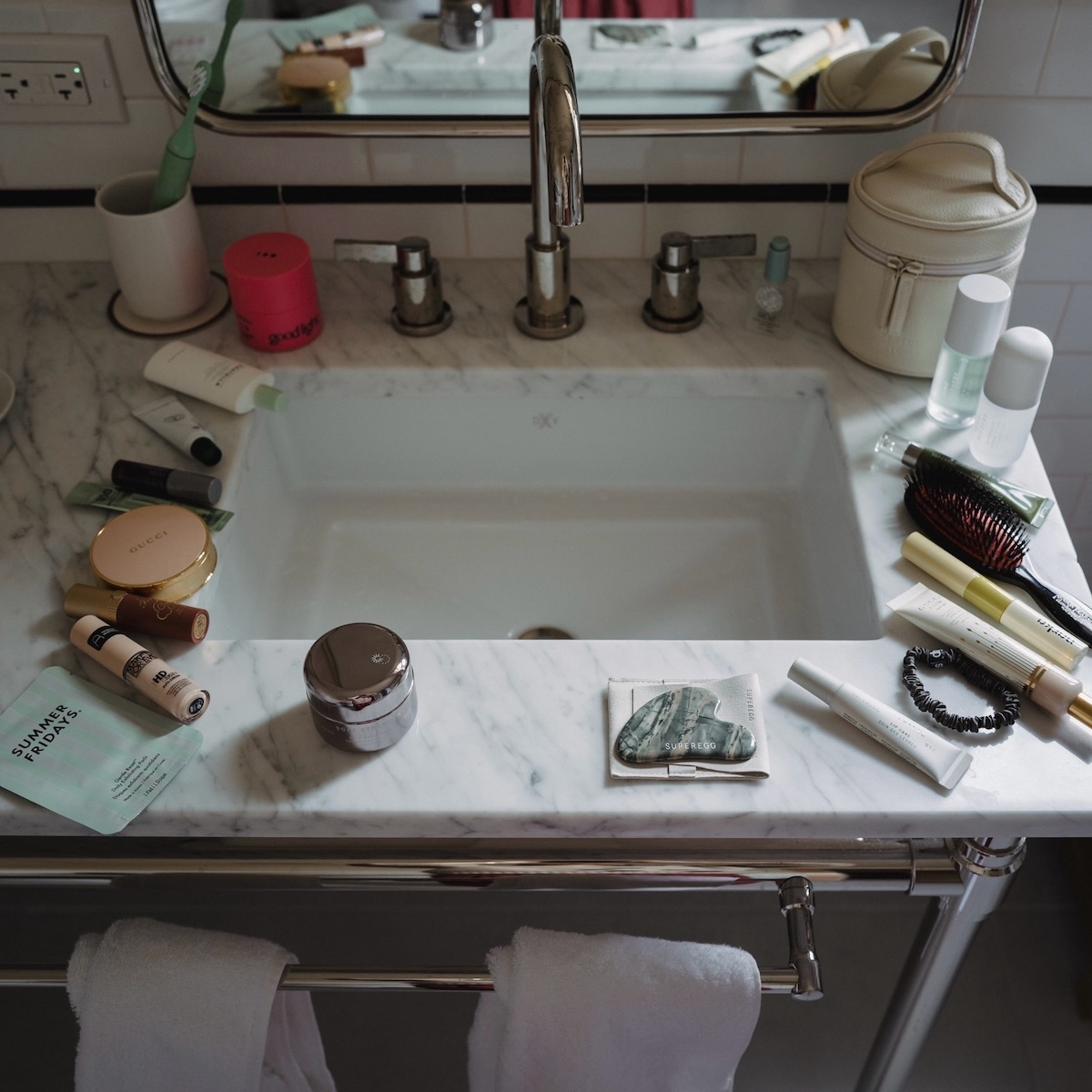 Bathroom vanity covered in beauty products.