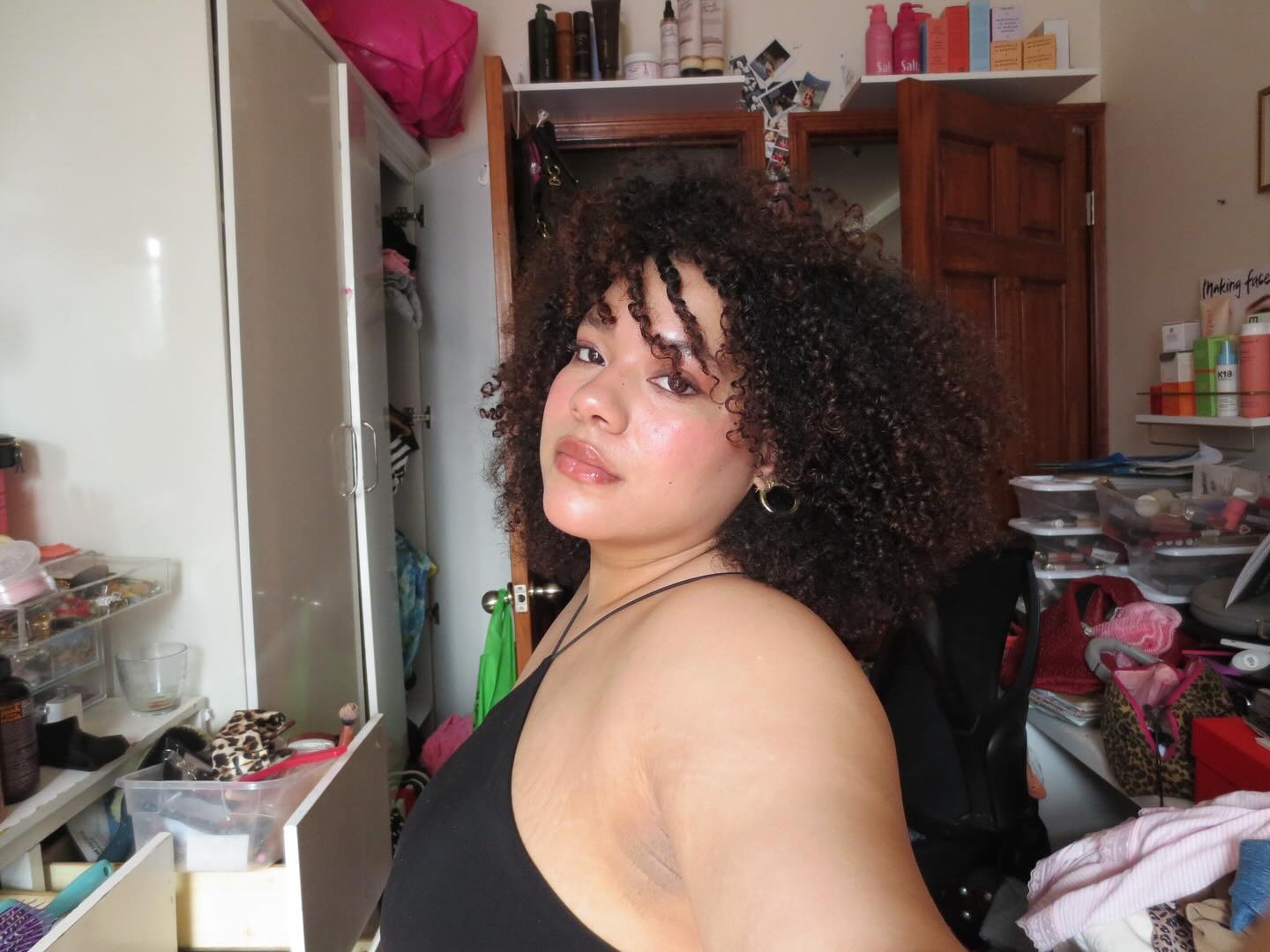 Creator @anaasmood taking a selfie with curly, dark hair and burnt amber highlights