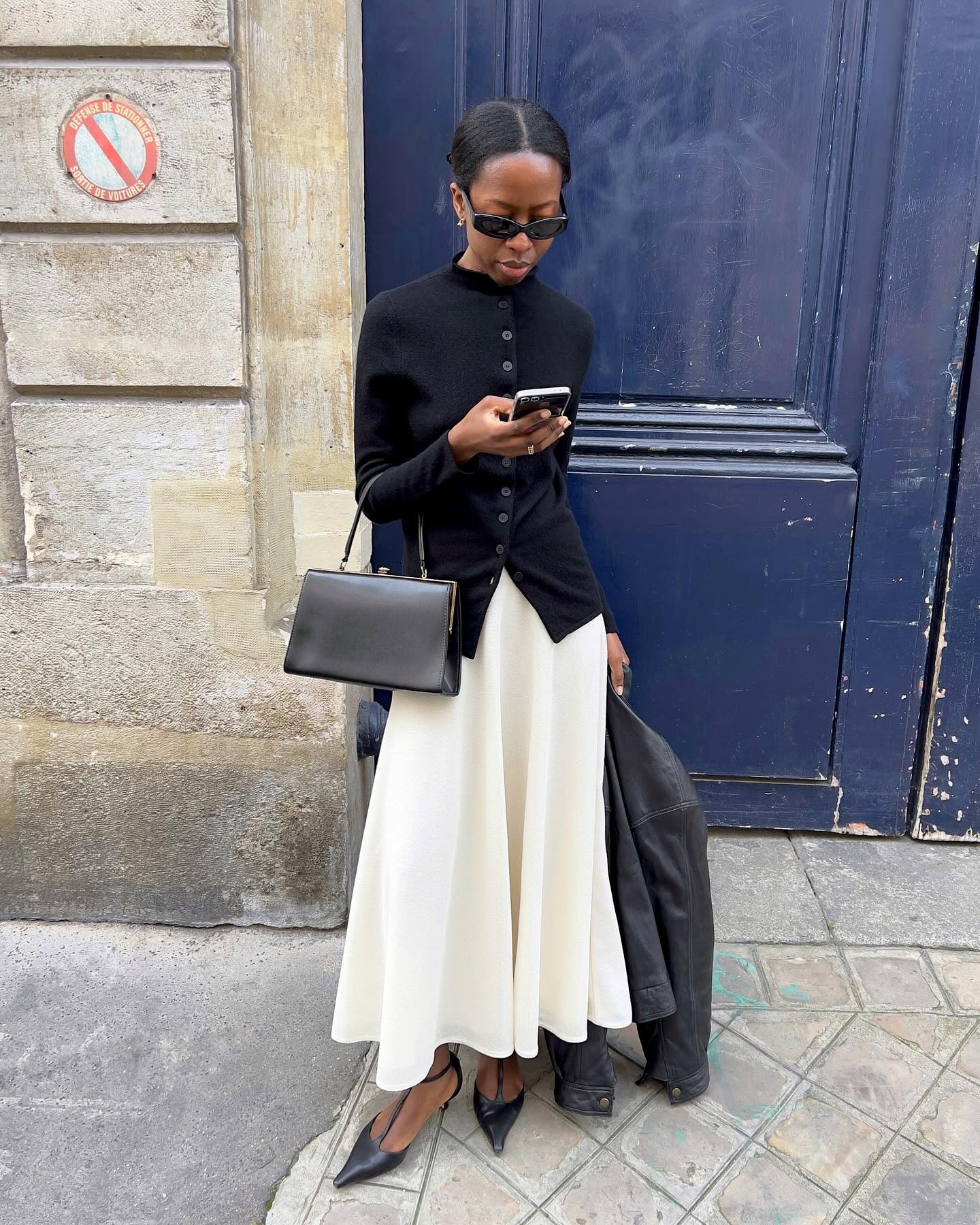 French influencer @sylviemus_ wears a midi skirt with t-bar heels and a black cardigan.