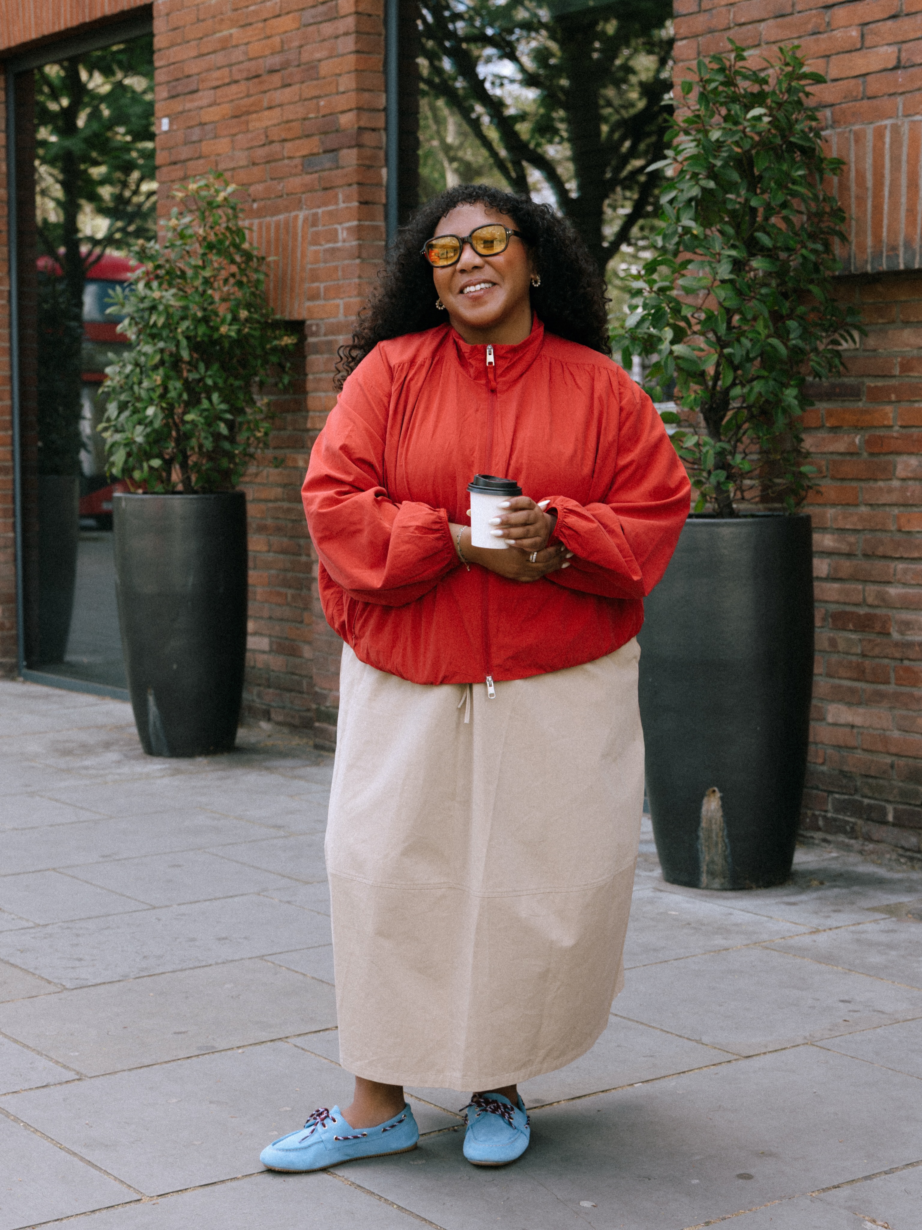 nicoleocran wears a red jacket, beige maxi skirt and  blue boat shoes